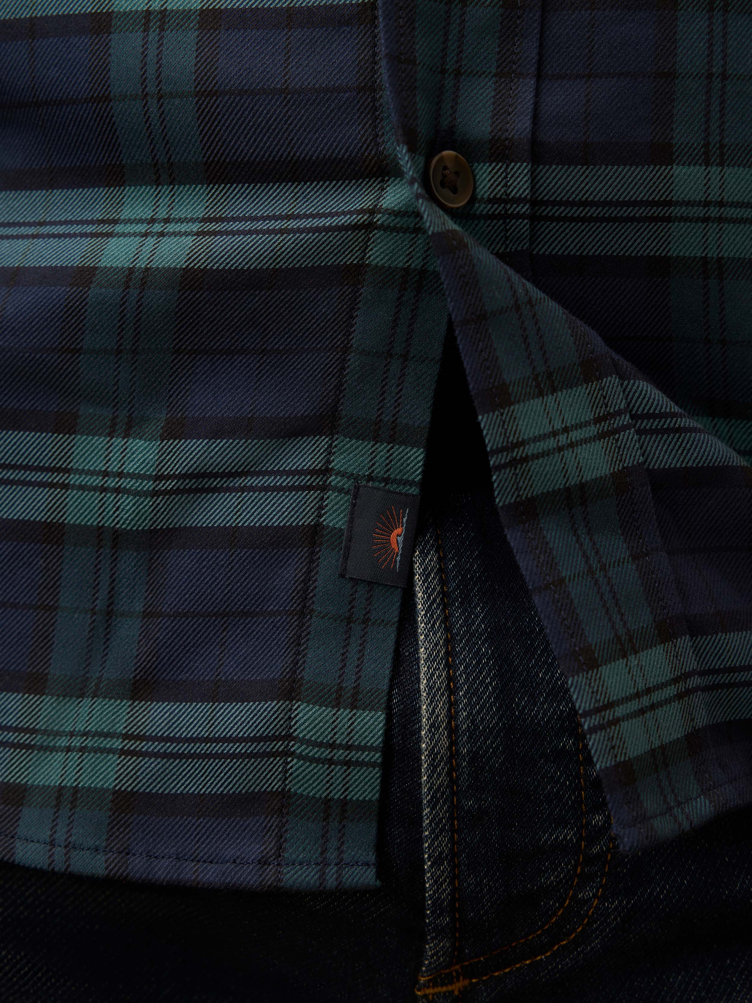 Close-up of a green and navy plaid shirt with a Faherty brand logo