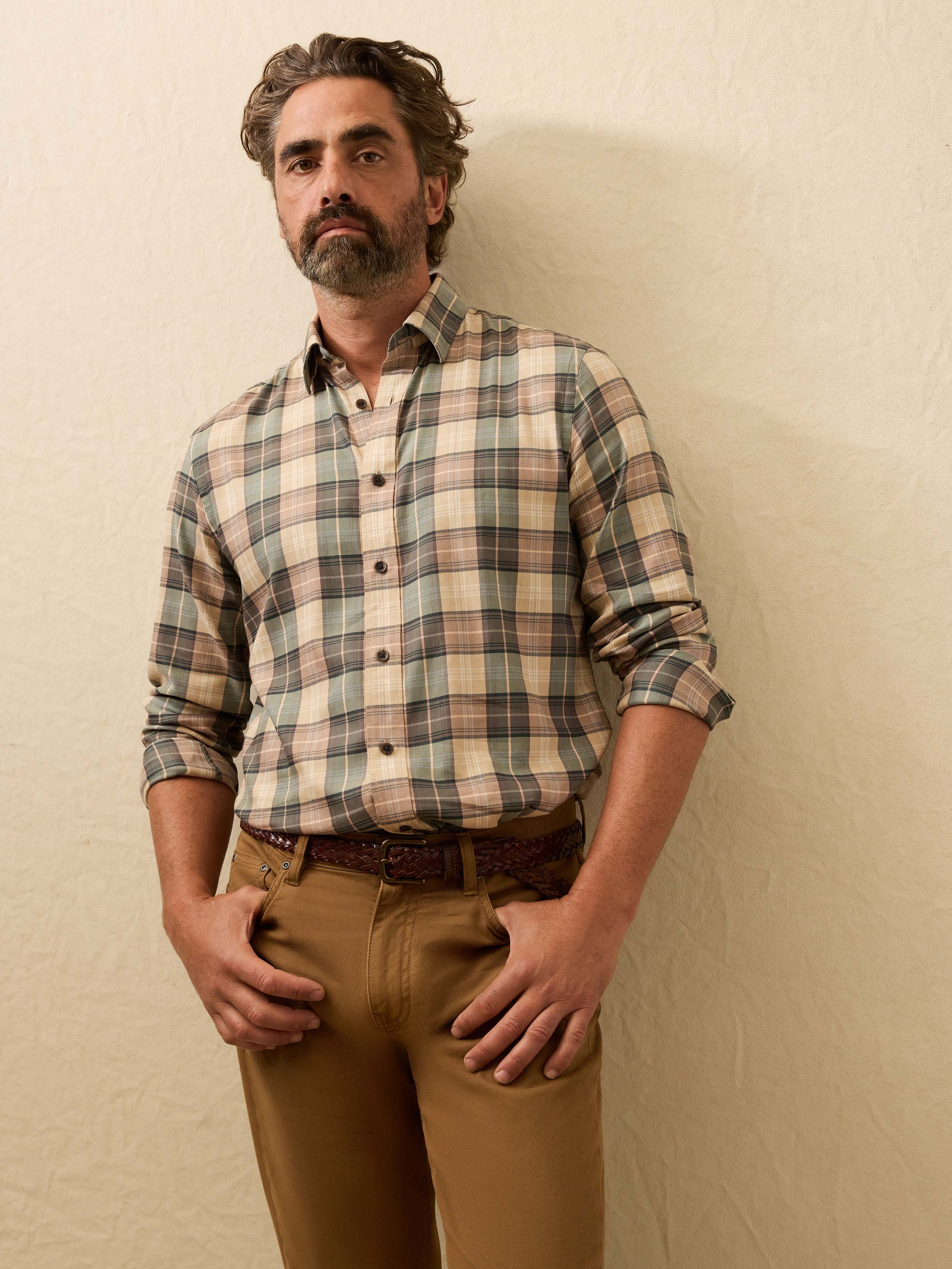 Man wearing a green and beige plaid shirt against a beige background