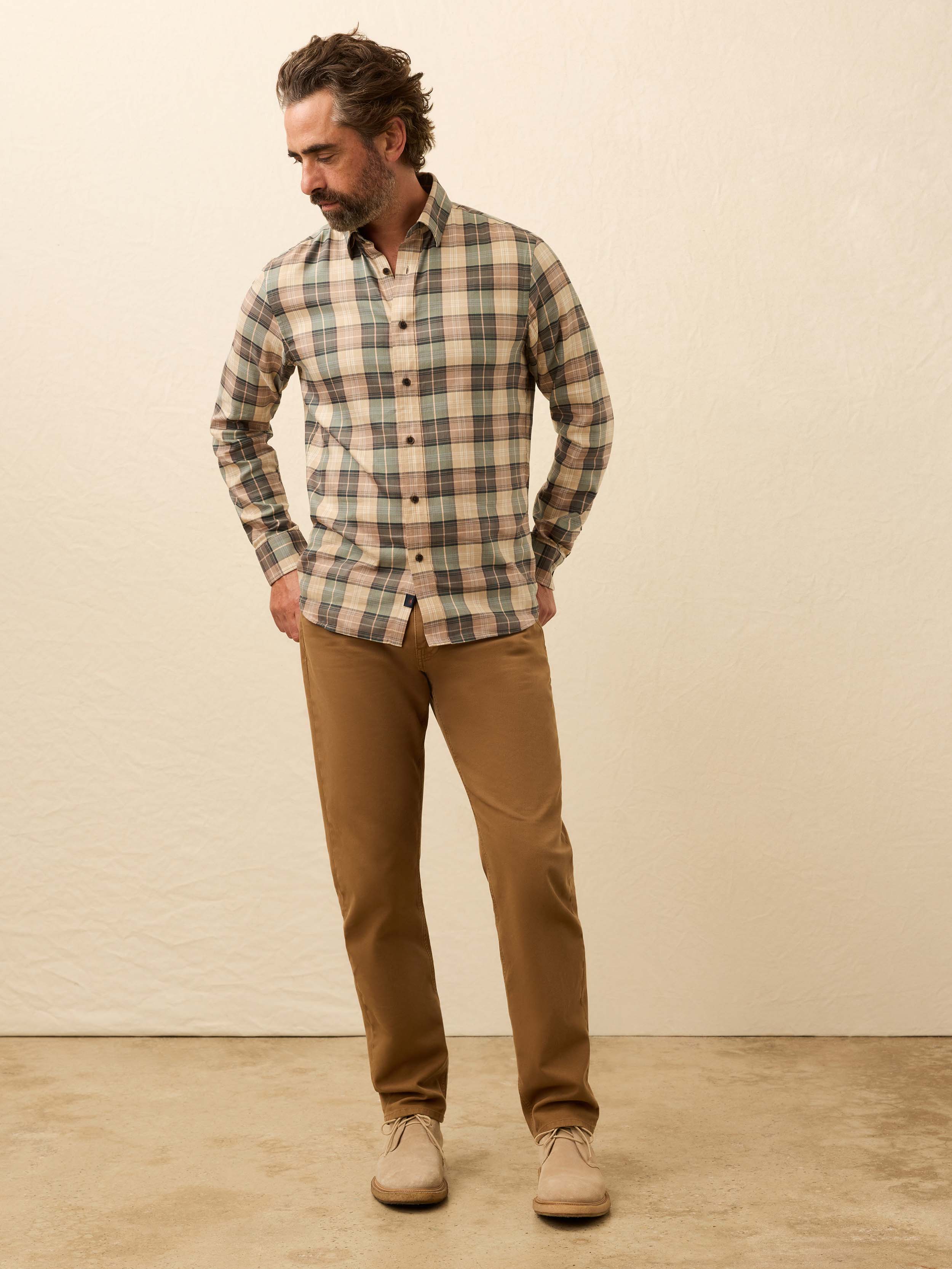 Man wearing a green and beige plaid shirt against a beige background