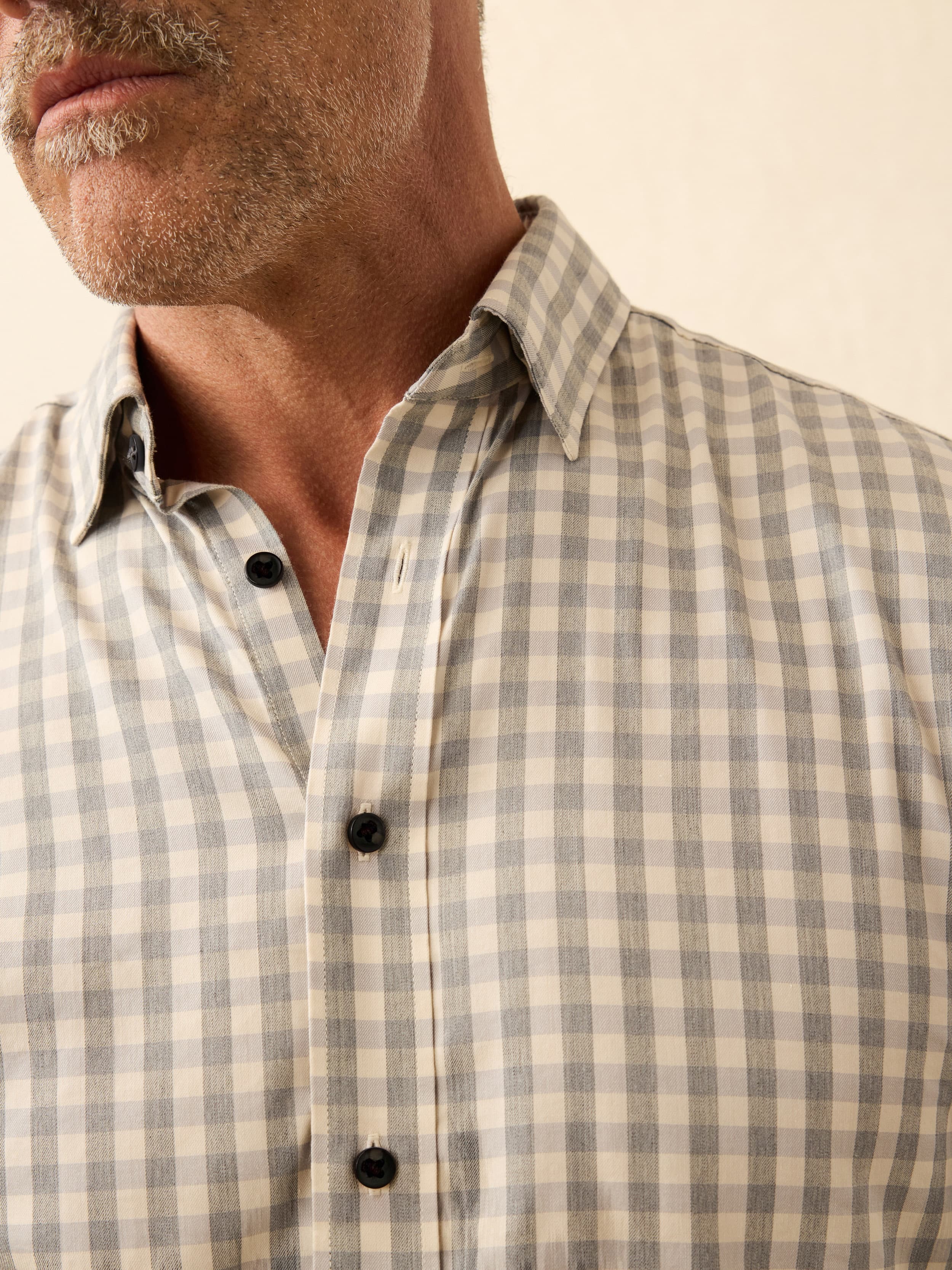 Man wearing a checkered shirt with a neutral background