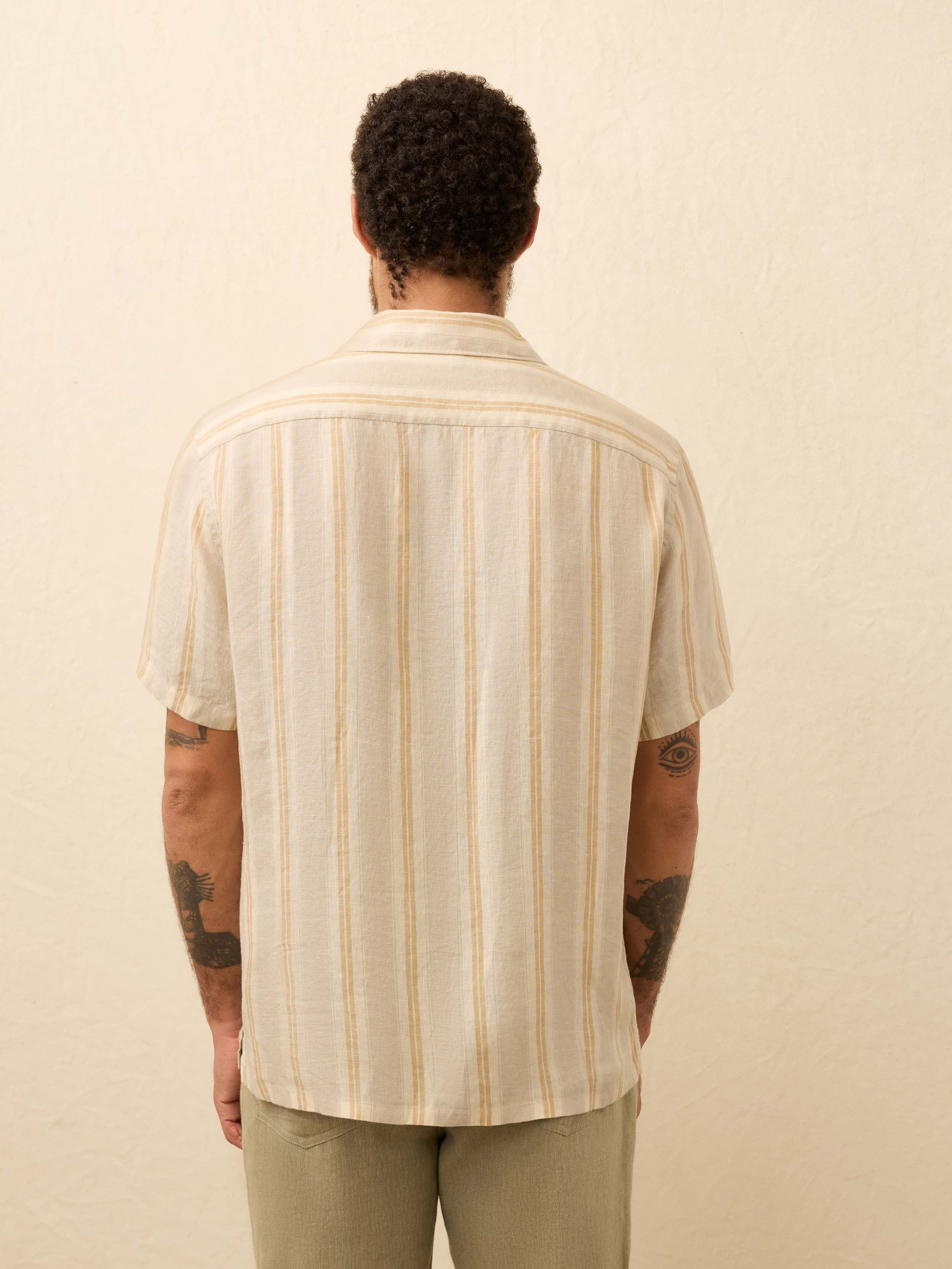 Man wearing a cream shirt with orange stripes against a beige background