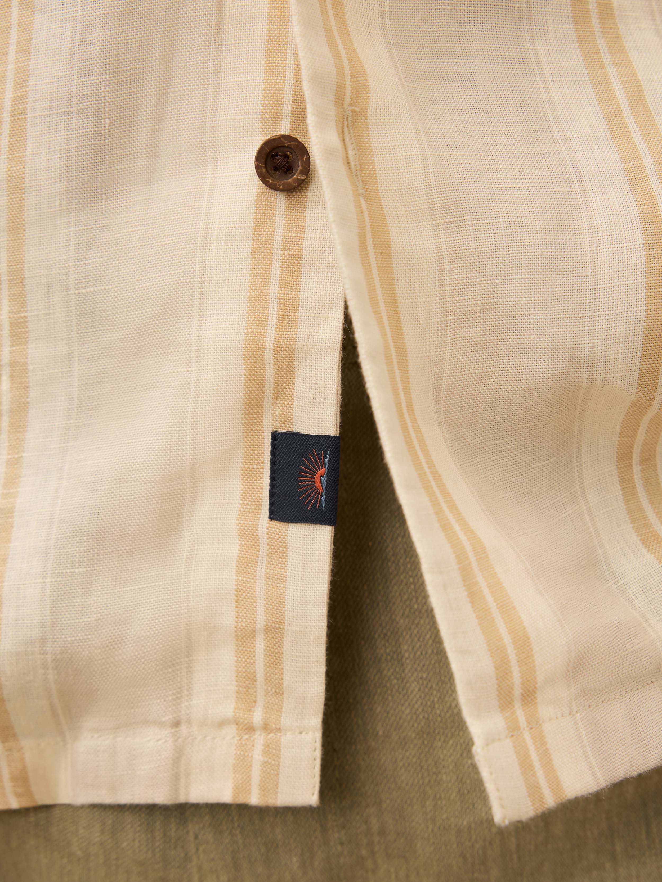 Close up of a man wearing a cream shirt with orange stripes