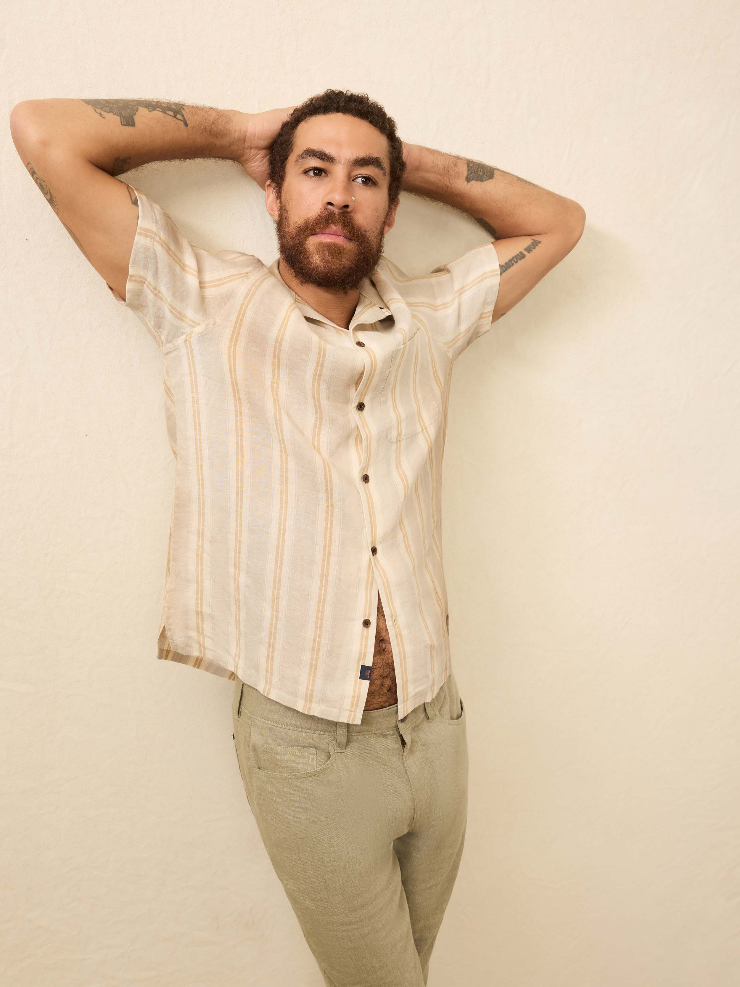 Man wearing a cream shirt with orange stripes against a beige background