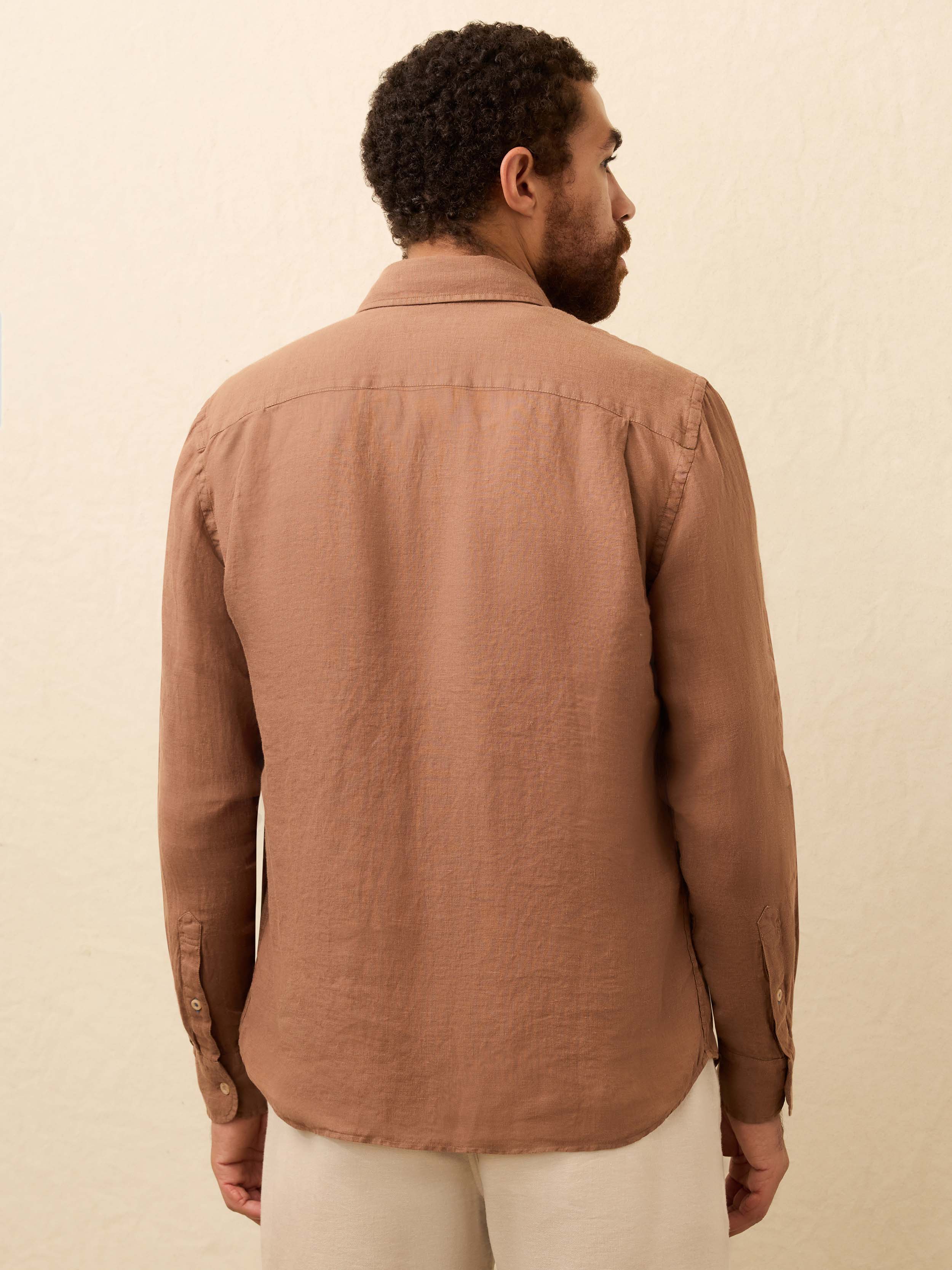 Man wearing a terracotta color long sleeve shirt against a beige background