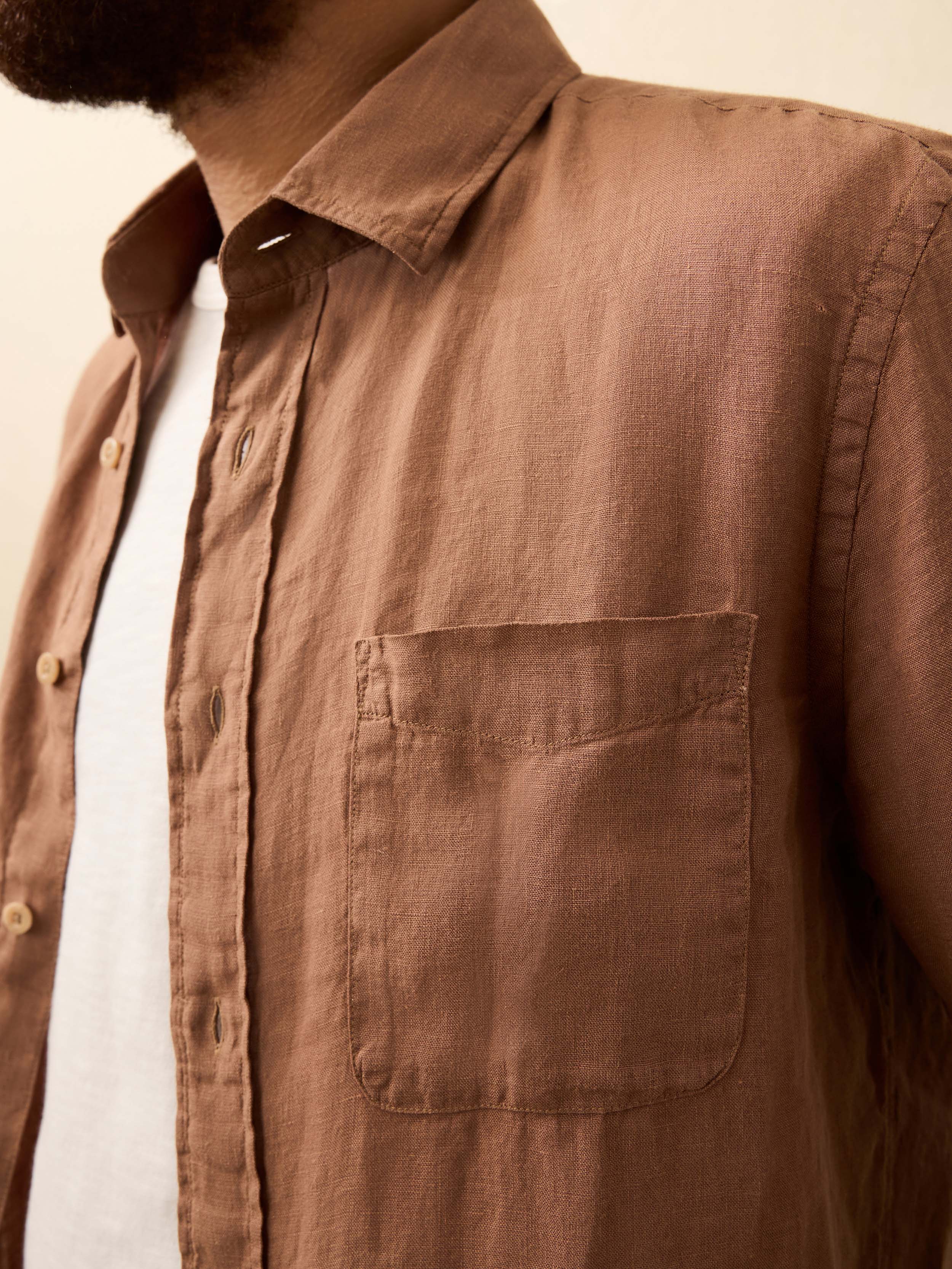 Man wearing a terracotta color long sleeve shirt against a beige background