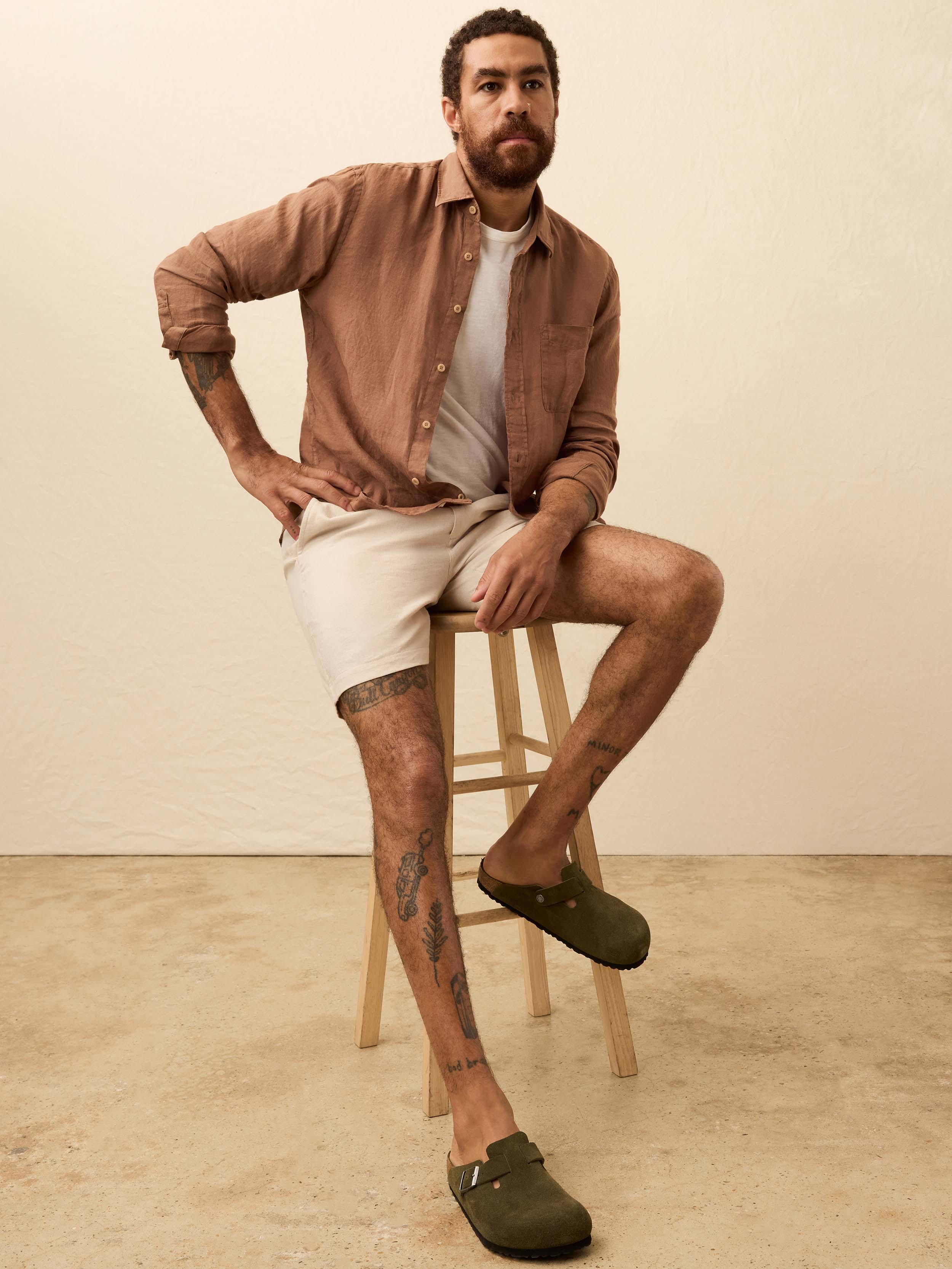 Man wearing a terracotta color long sleeve shirt against a beige background