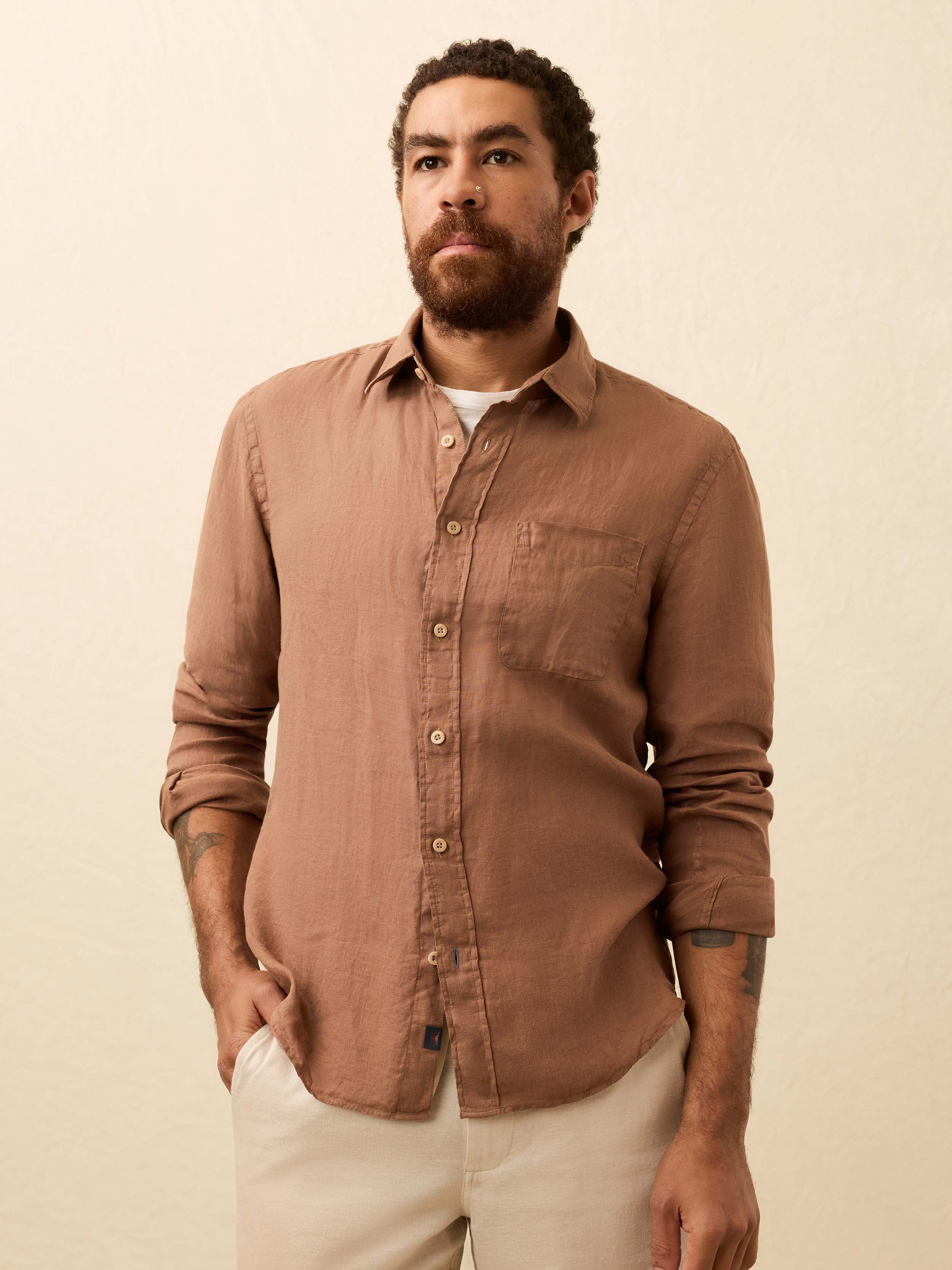 Man wearing a terracotta color long sleeve shirt against a beige background