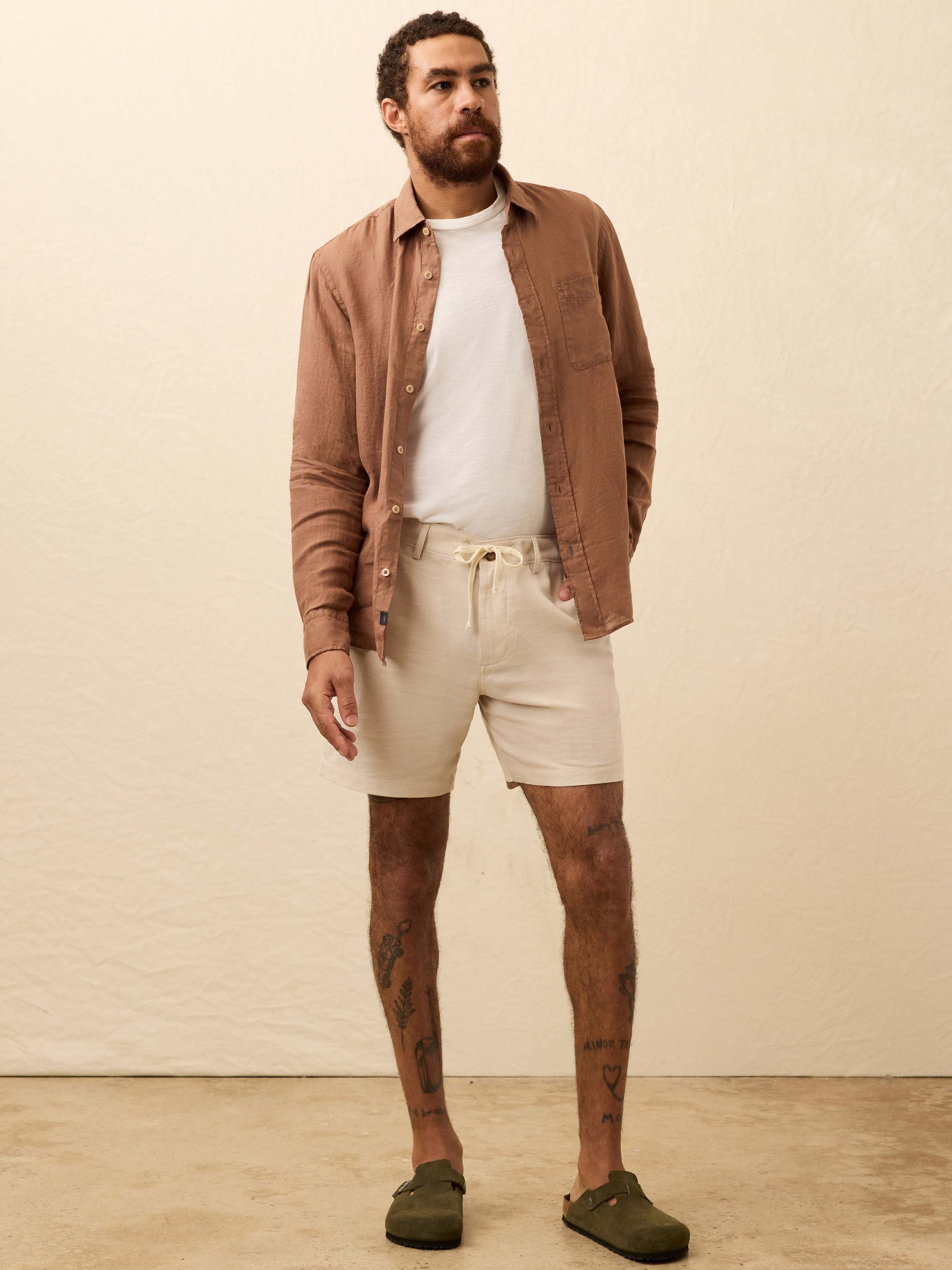 Man wearing a terracotta color long sleeve shirt against a beige background