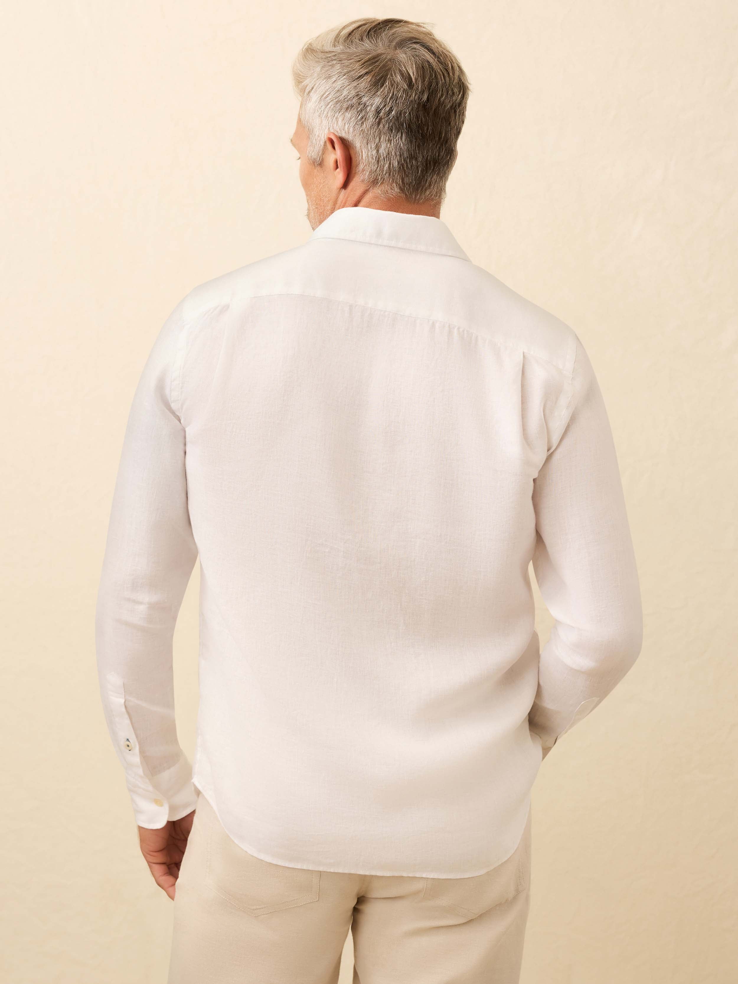 Man wearing a white linen shirt and beige pants against a beige background