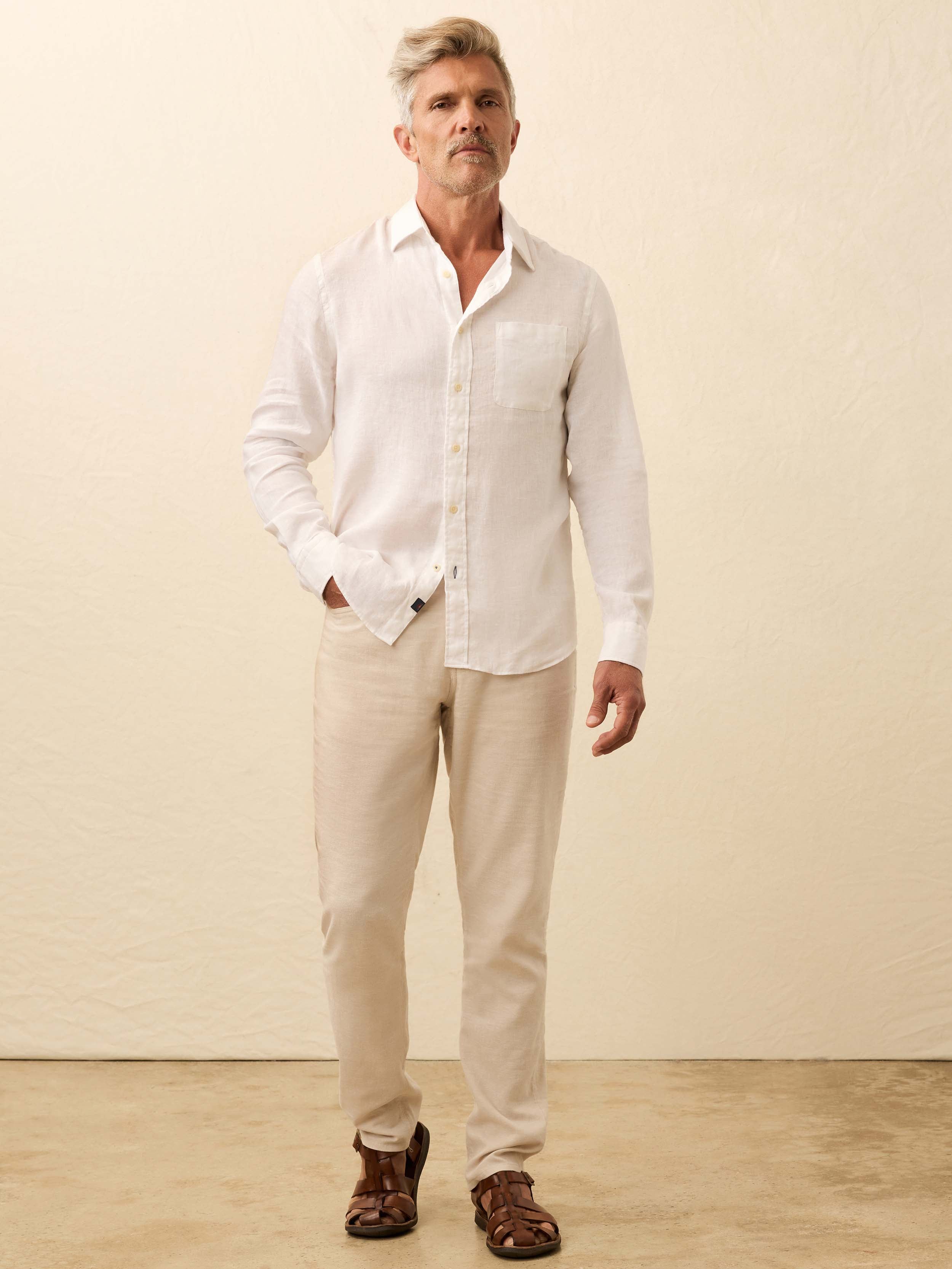 Man wearing a white linen shirt and beige pants against a beige background