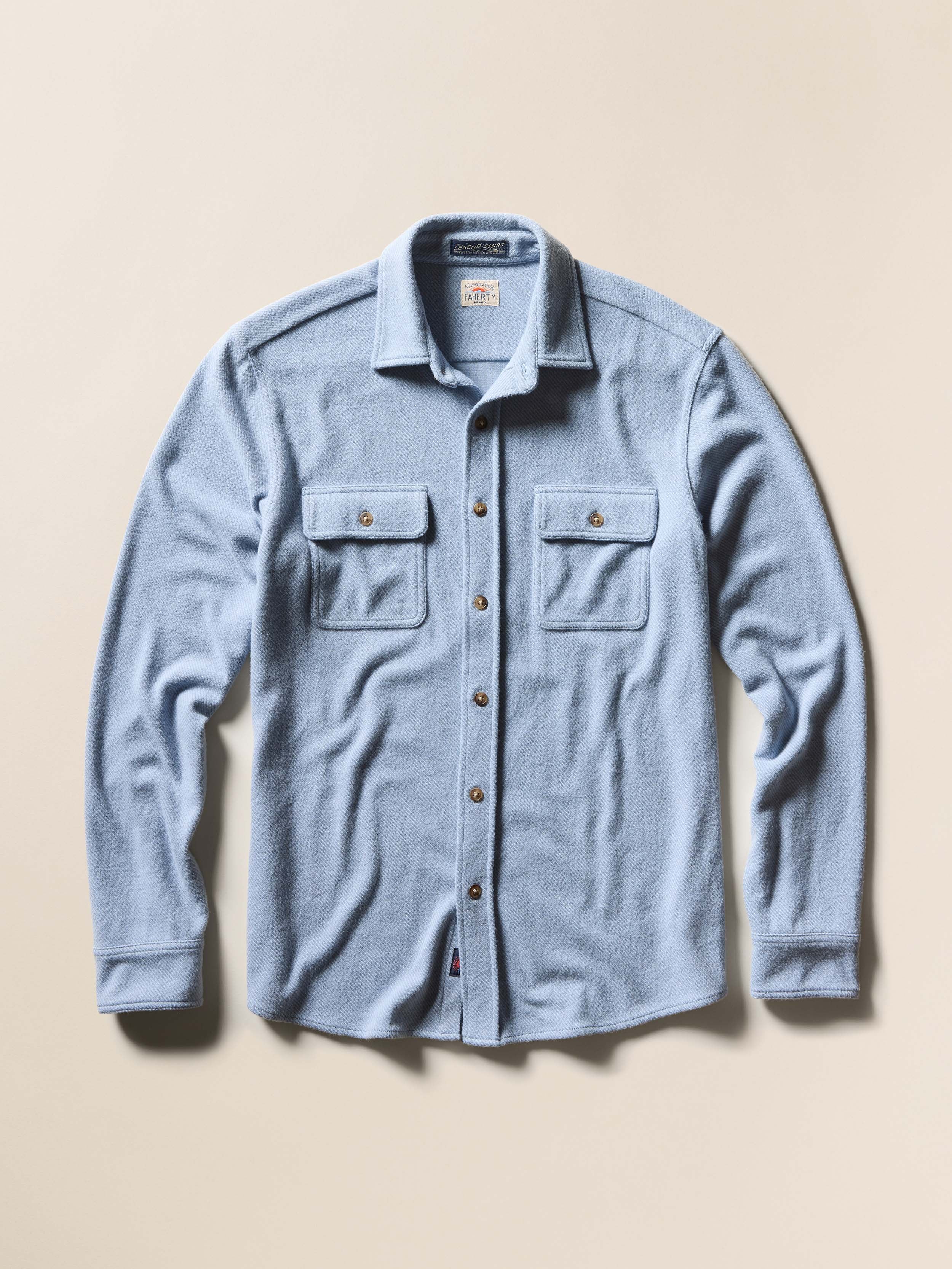 Blue button-up shirt with two chest pockets on a beige background