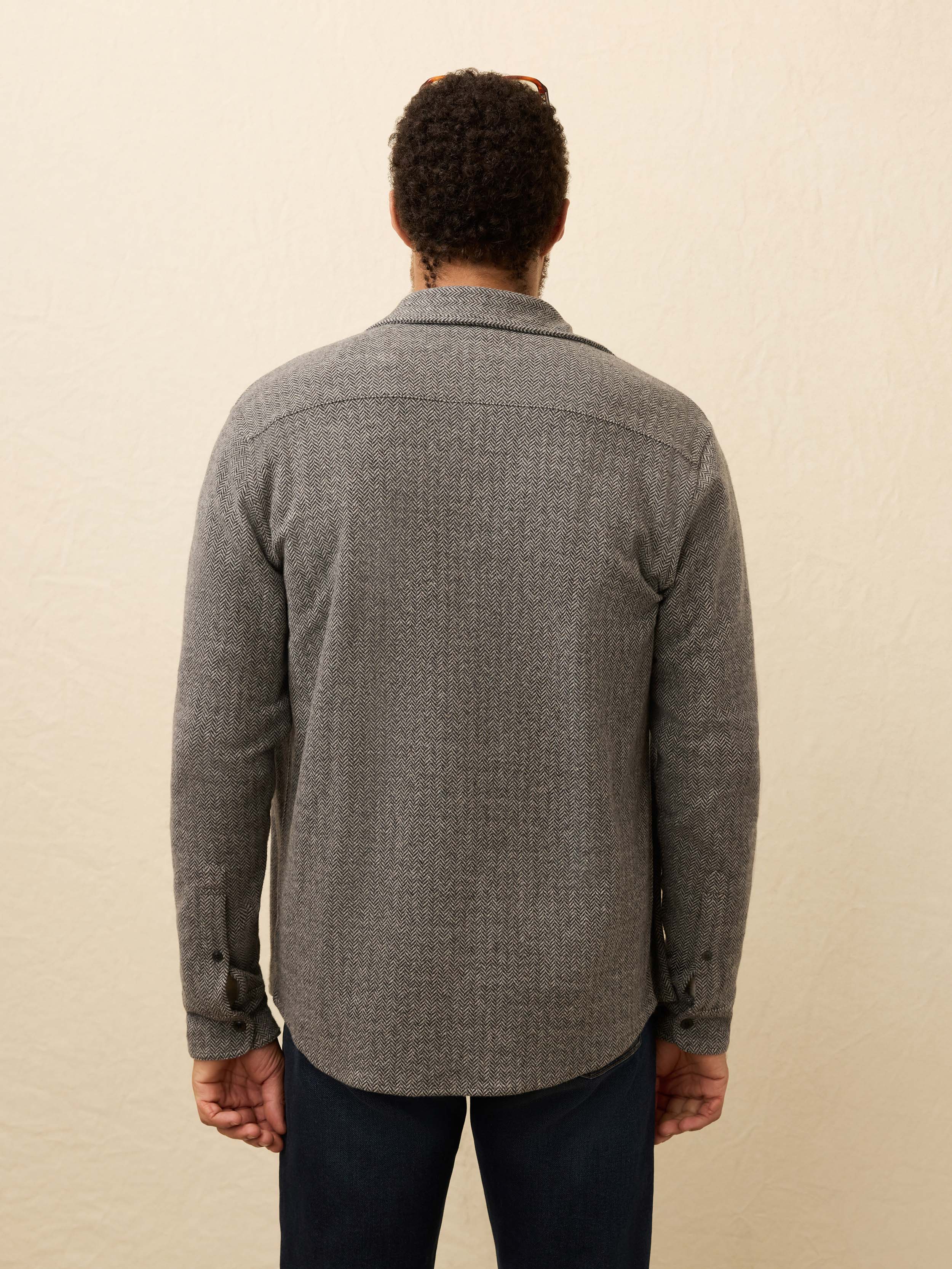 Person wearing a gray flannel shirt against a beige background