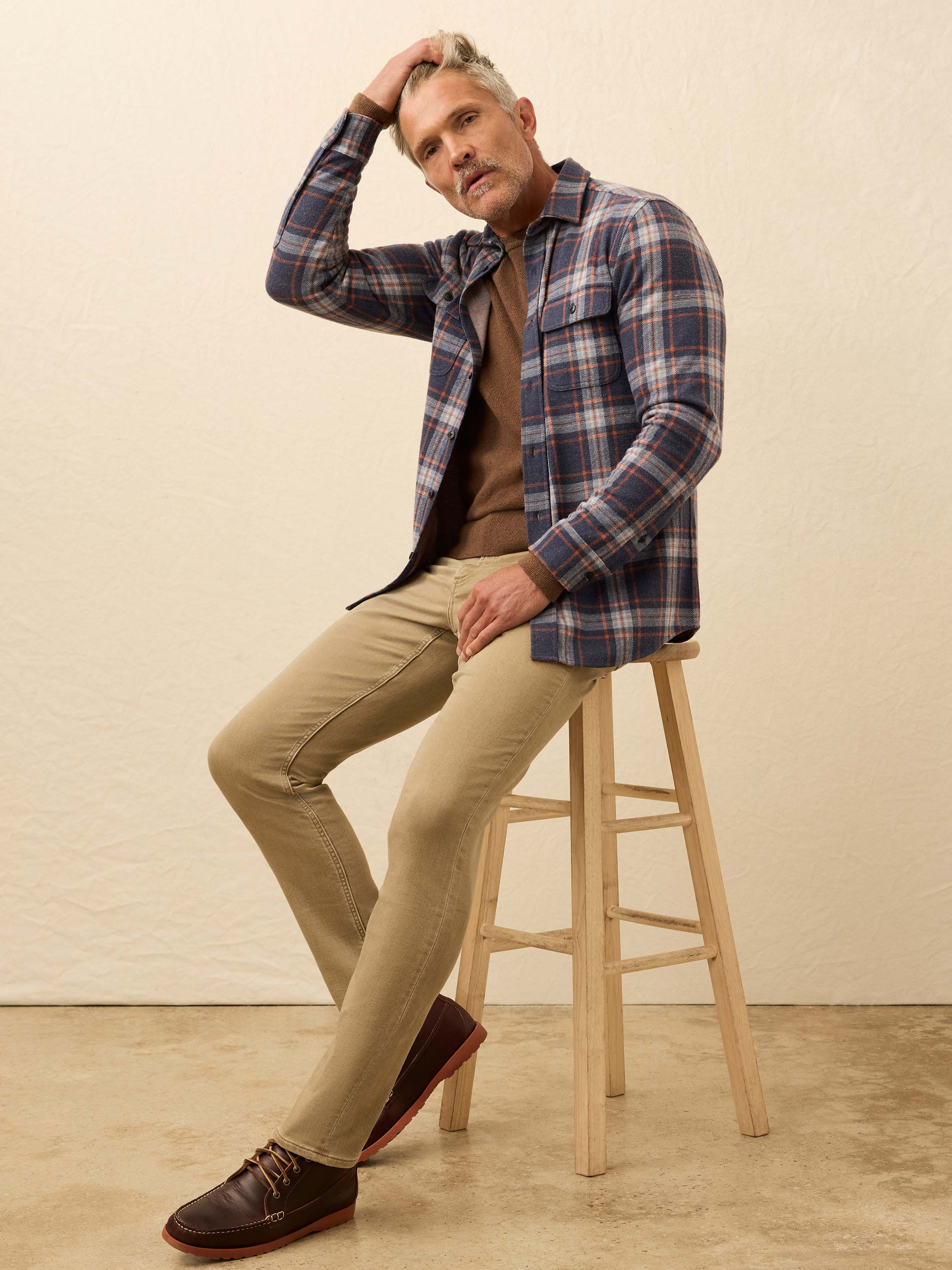 Man wearing a blue plaid long sleeve shirt against a beige background