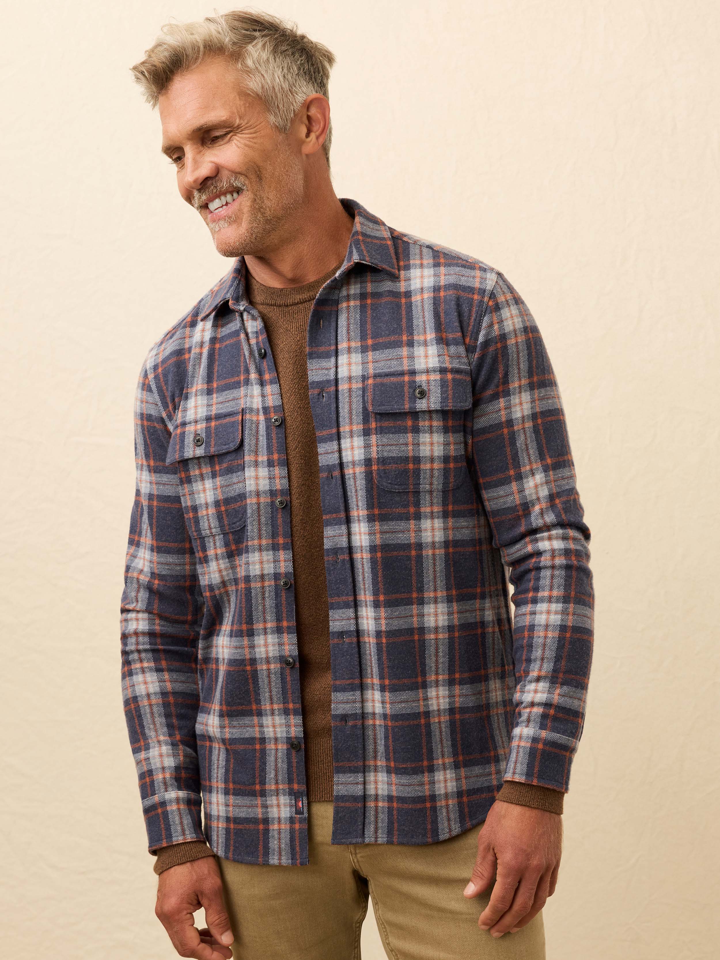 Man wearing a blue plaid long sleeve shirt against a beige background