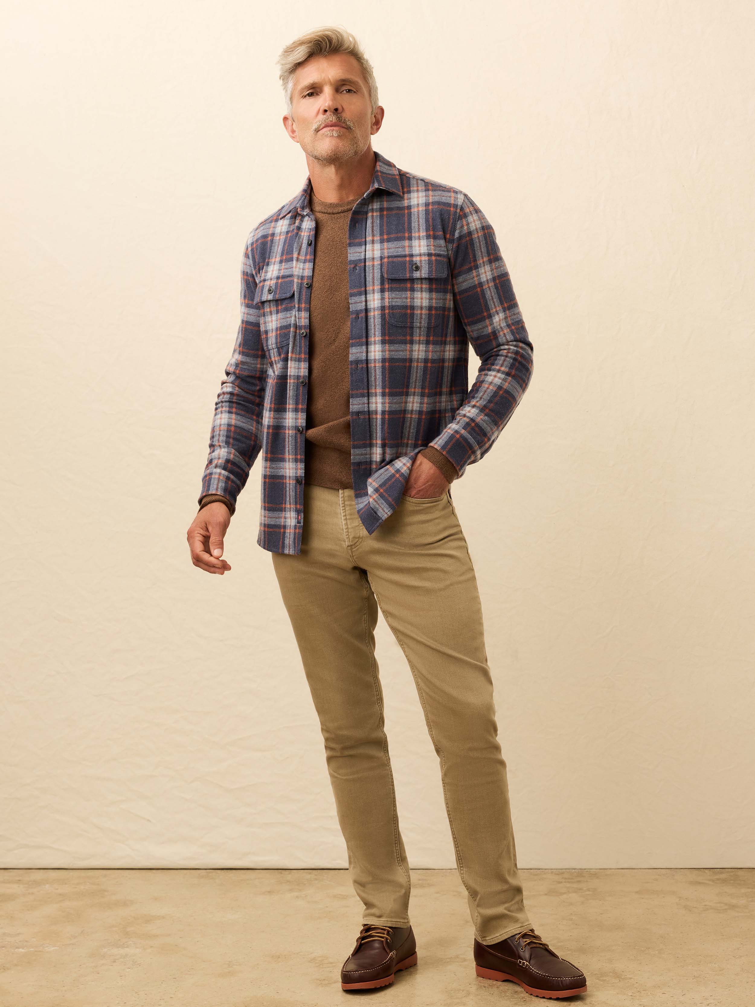 Man wearing a blue plaid long sleeve shirt against a beige background