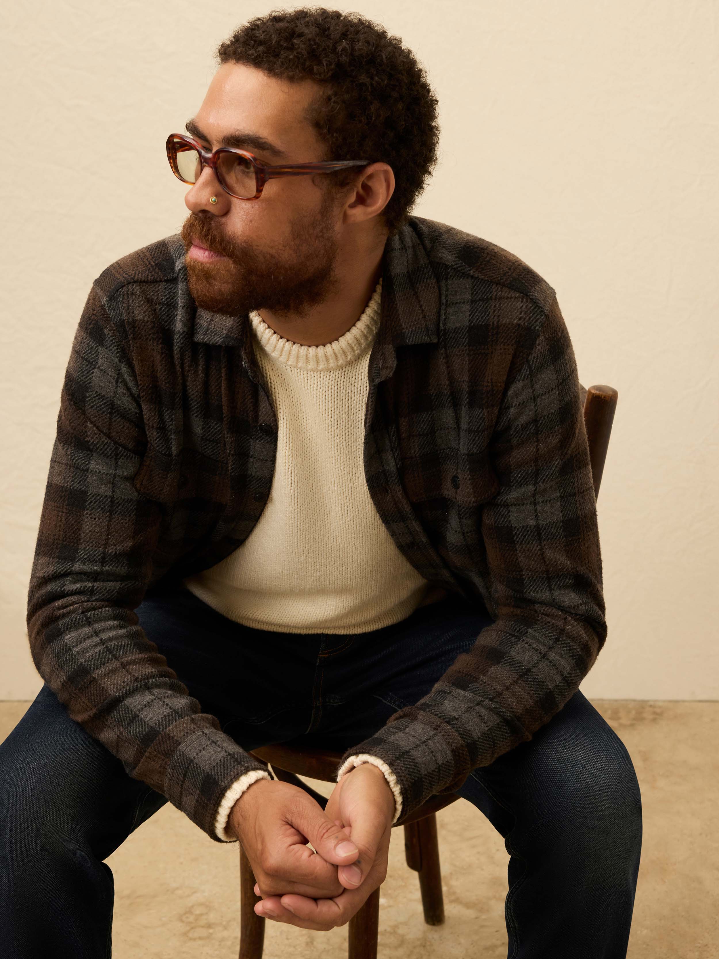 Man wearing a brown and grey plaid shirt, against a beige background