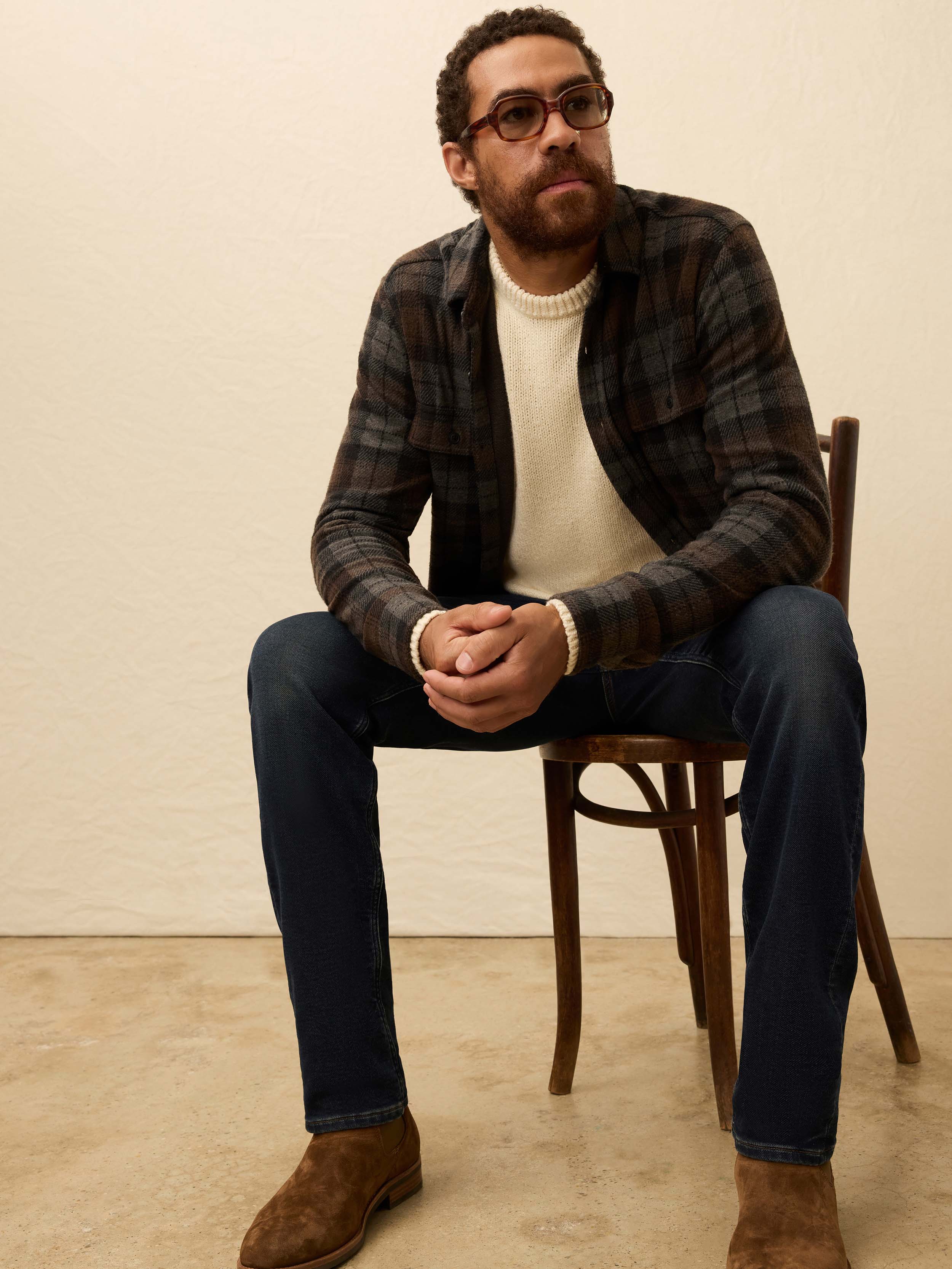 Man wearing a brown and grey plaid shirt, against a beige background