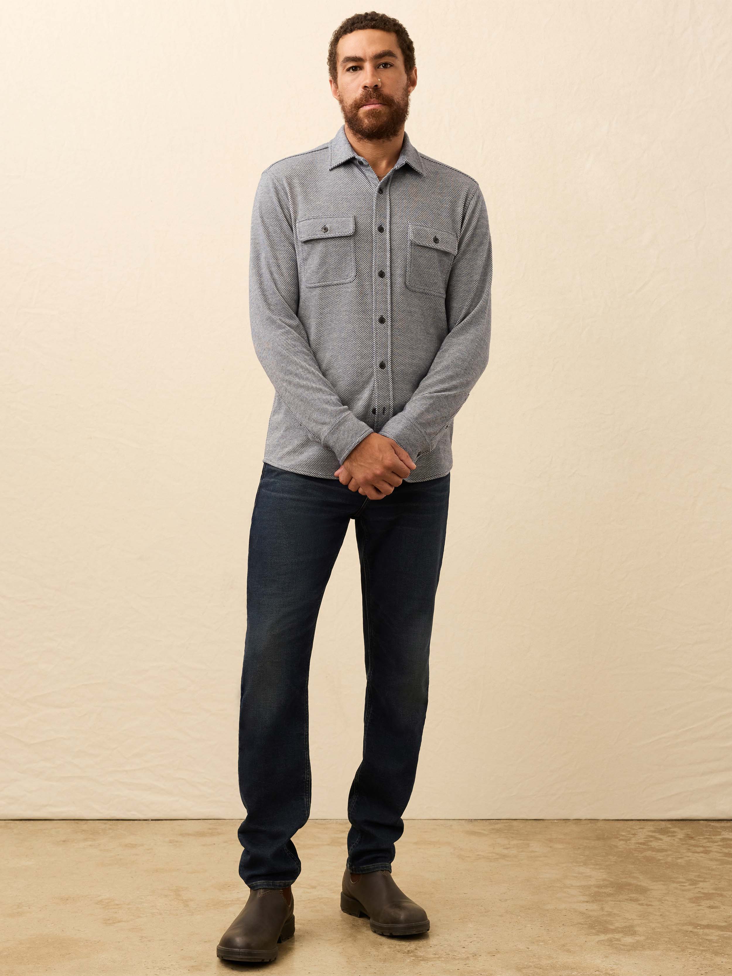 Man wearing a gray button-up long sleeve shirt against a beige background