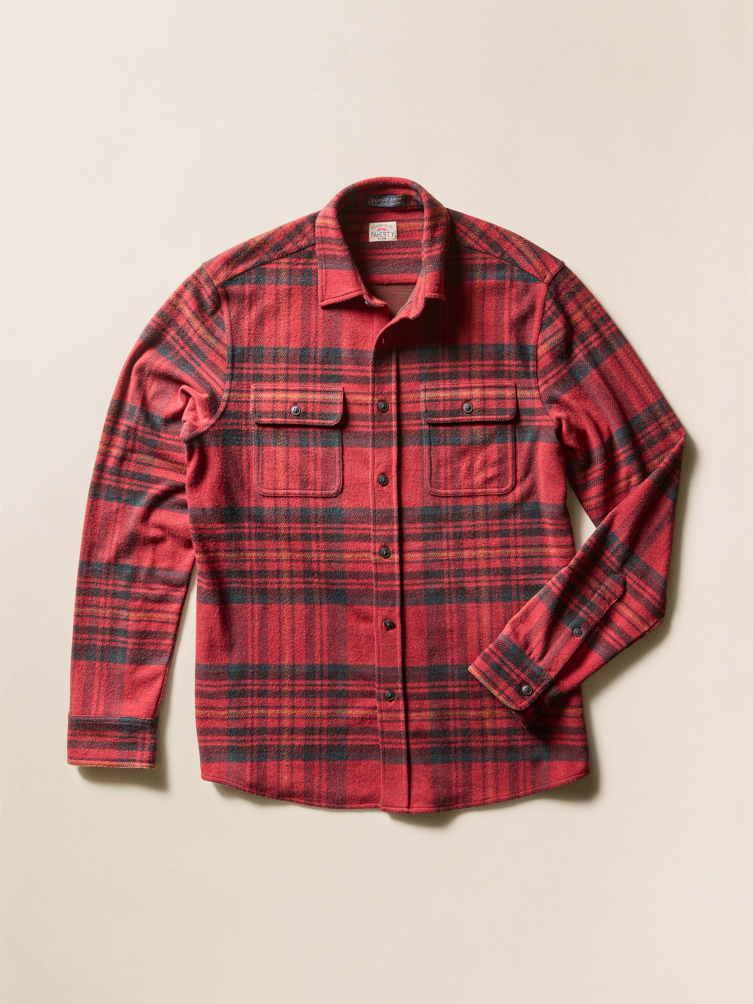 Flat image of a red and black plaid long-sleeve button-up shirt on a beige background