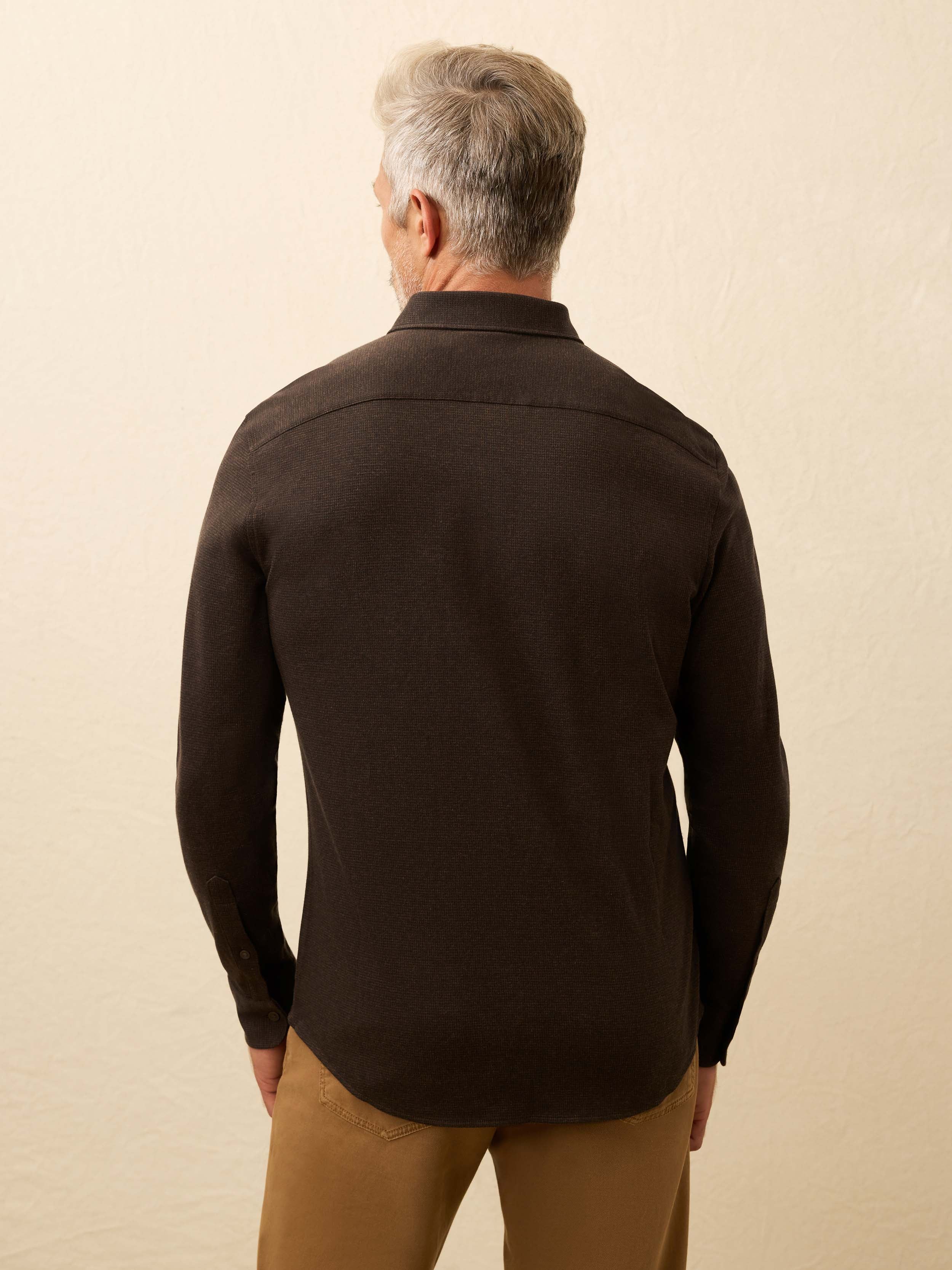 Man is wearing a brown gingham shirt against a beige background