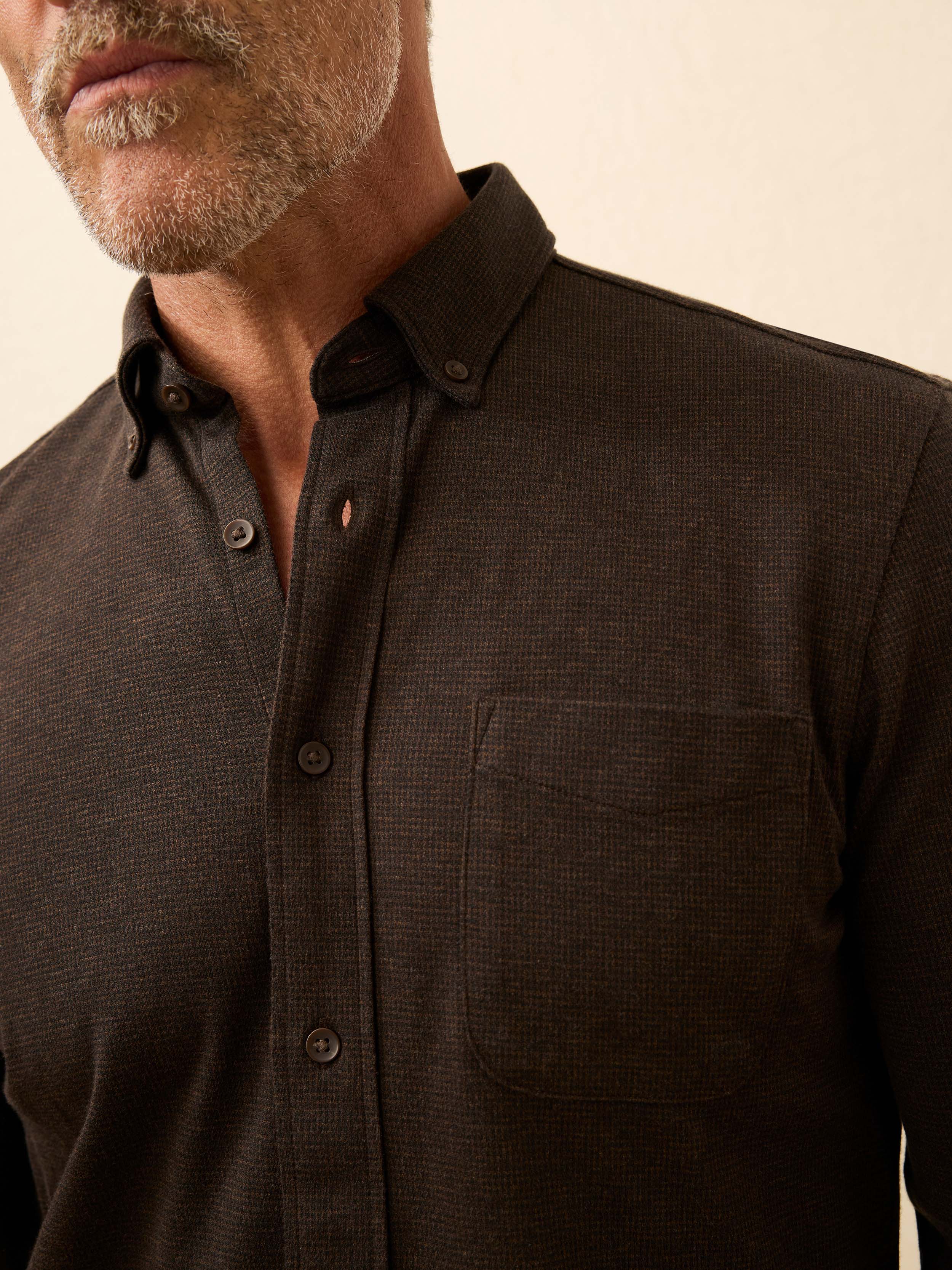 Man is wearing a brown gingham shirt against a beige background