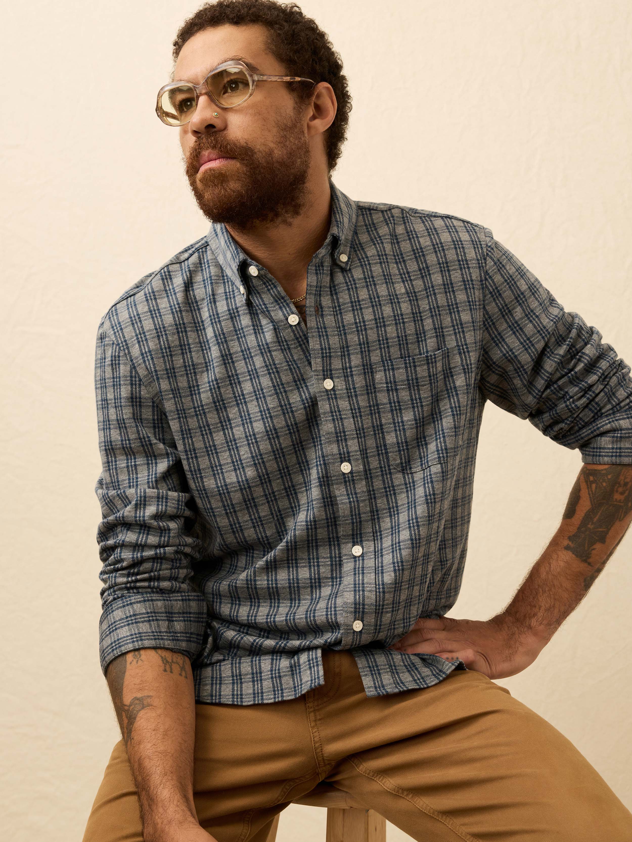 Man wearing a blue and grey plaid shirt against a beige background