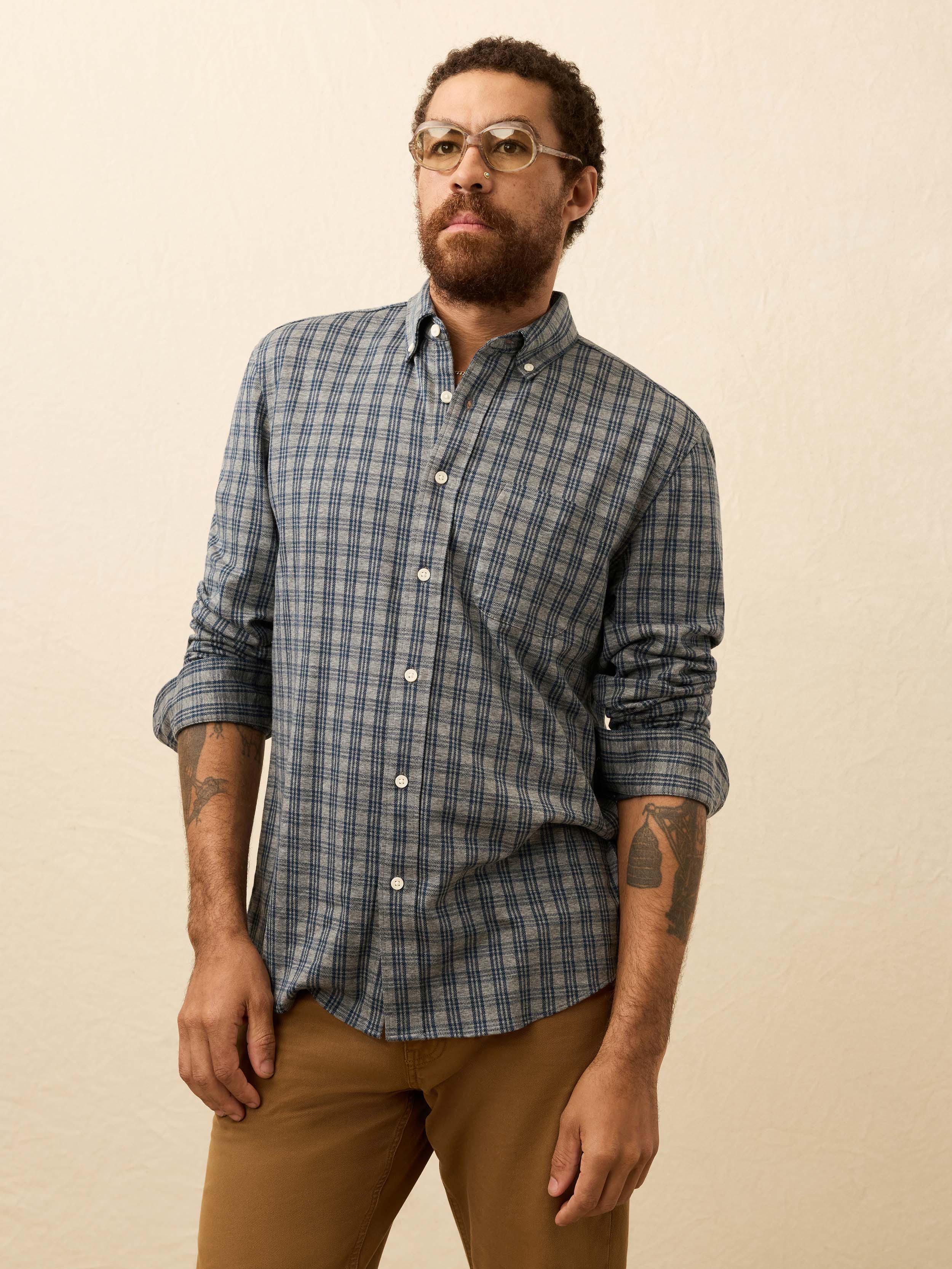 Man wearing a blue and grey plaid shirt against a beige background