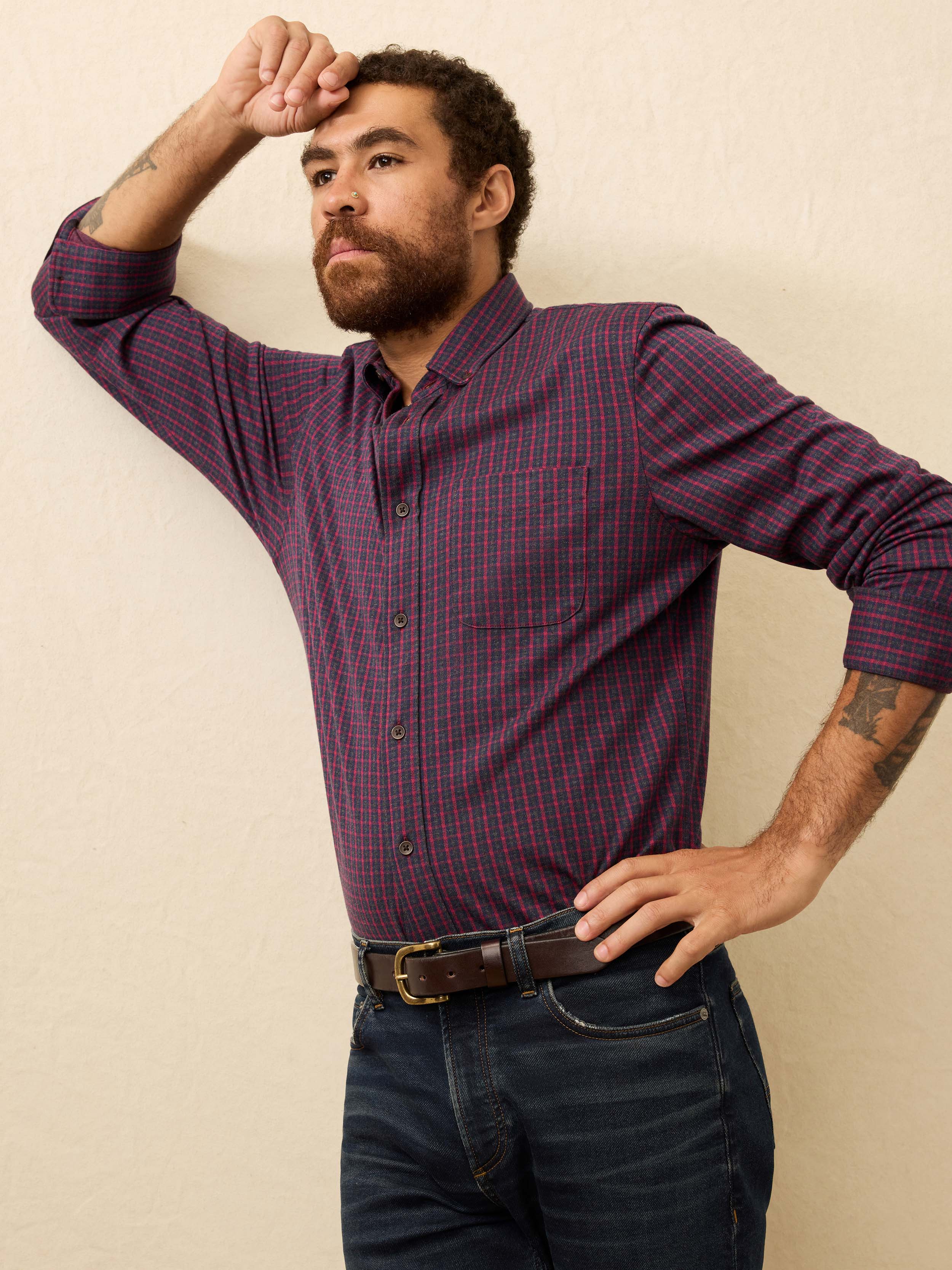 Man wearing a red and blue checkered shirt against a beige background