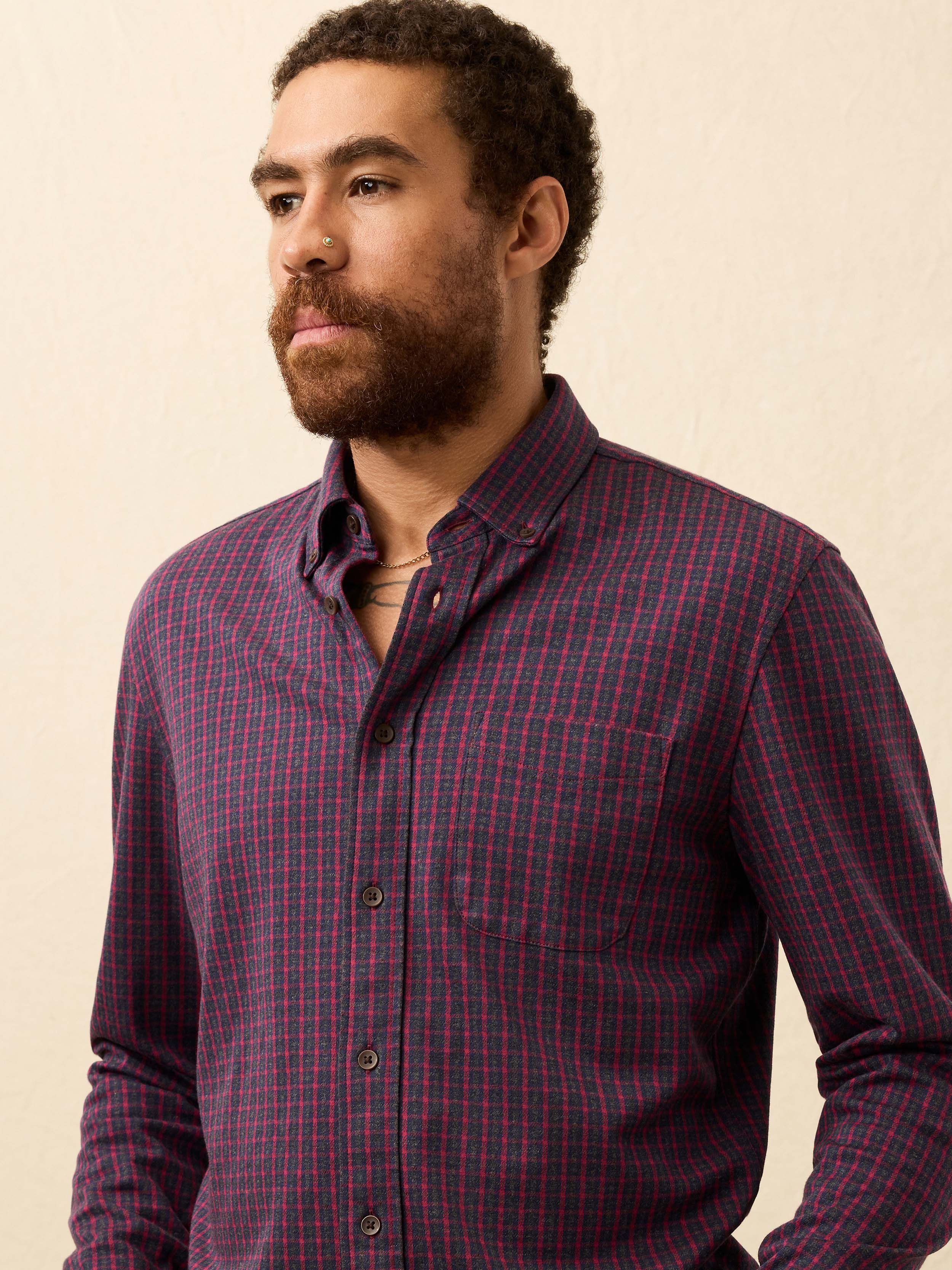 Man wearing a red and blue checkered shirt against a beige background