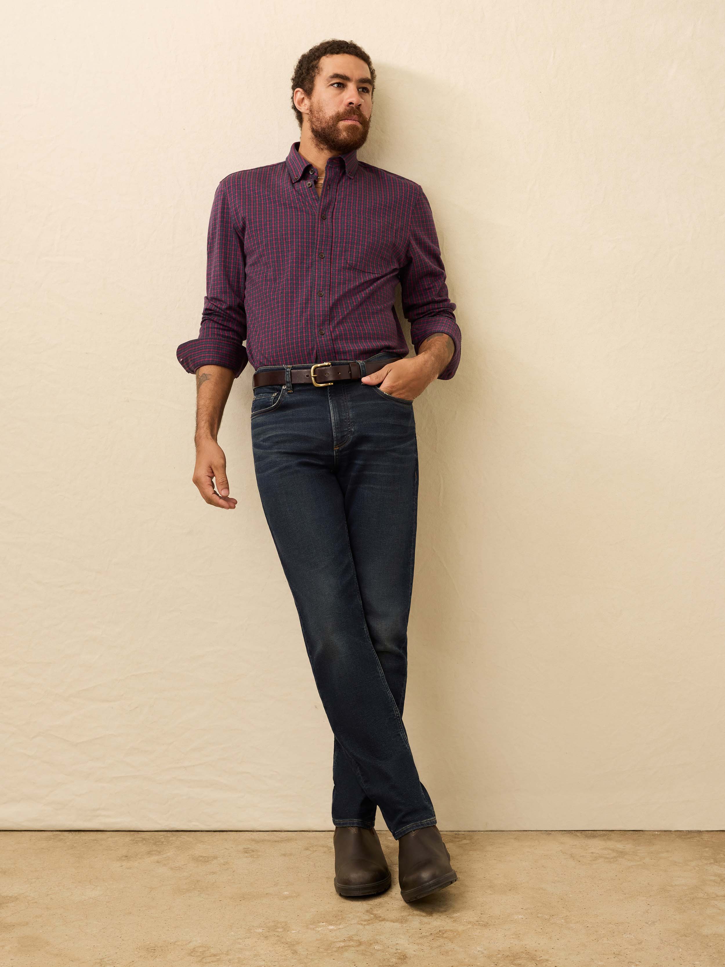 Man wearing a red and blue checkered shirt against a beige background