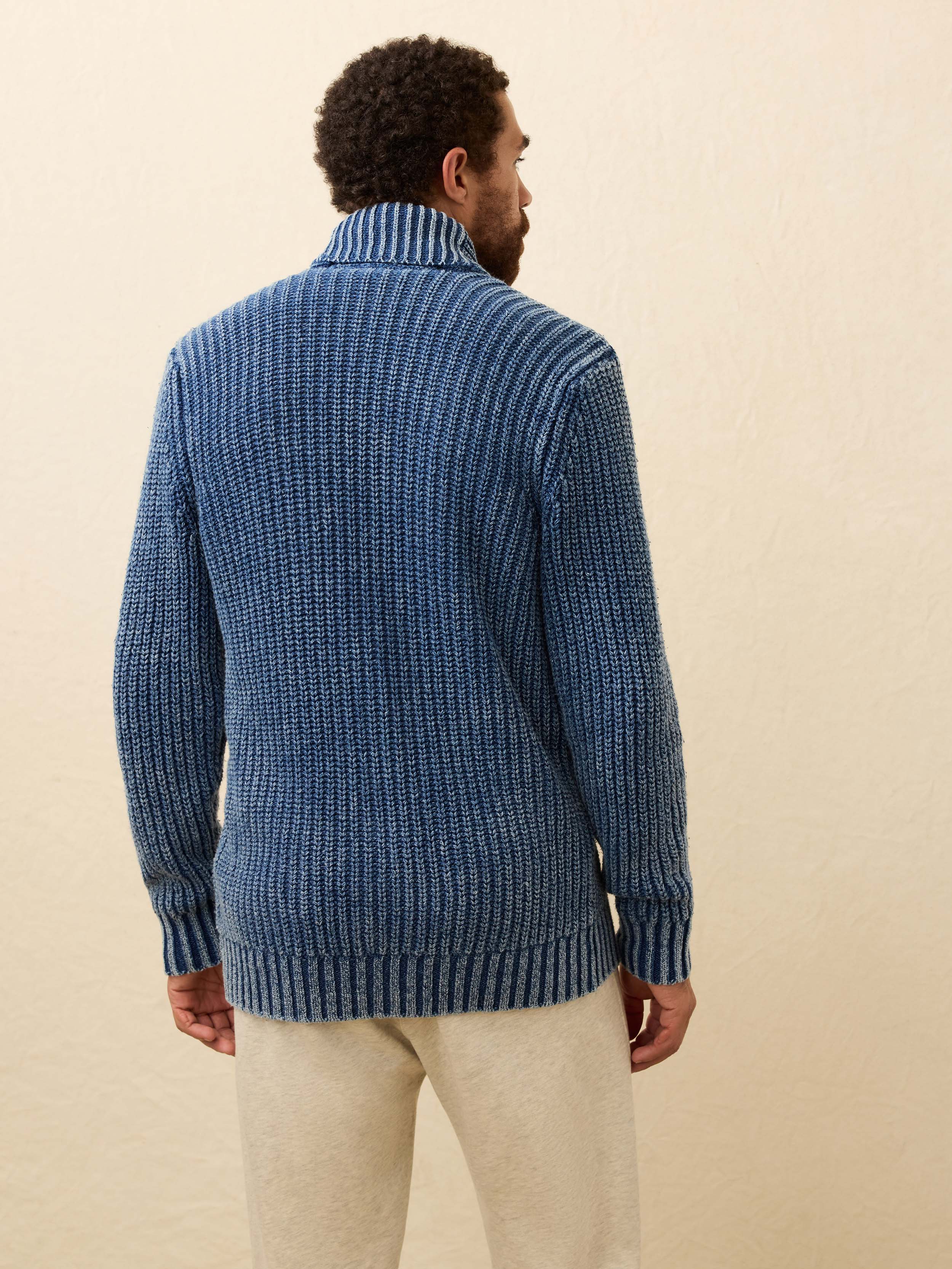 Man wearing a blue knitted cardigan on a beige background