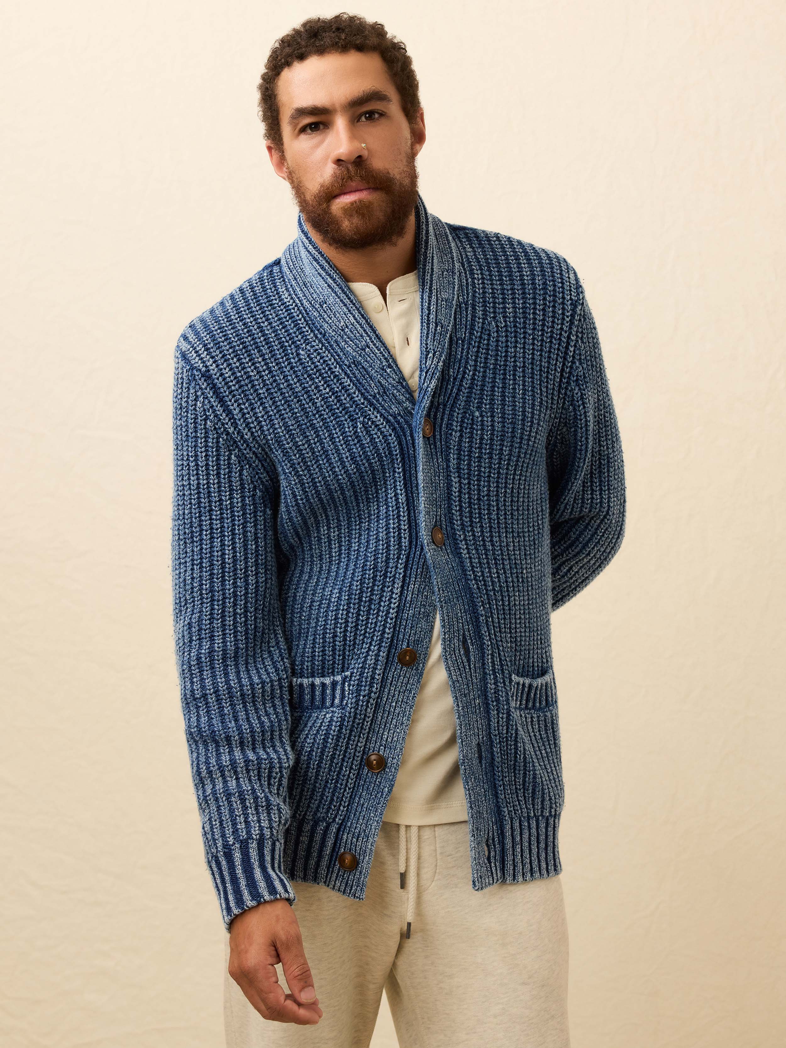 Man wearing a blue knitted cardigan on a beige background