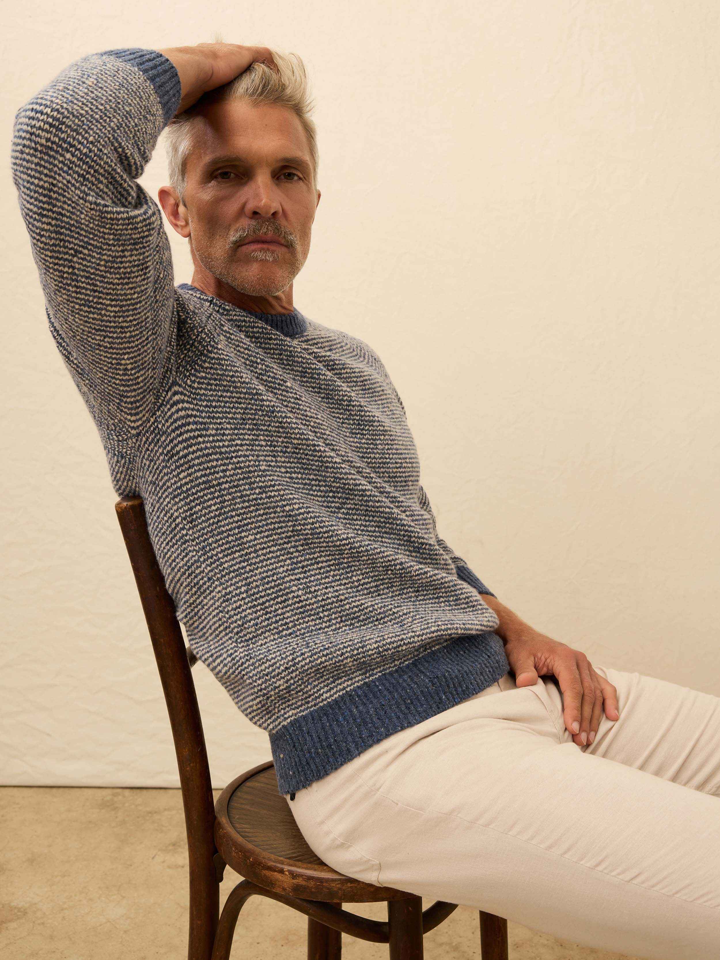 Man is wearing a blue and white sweater against a beige background