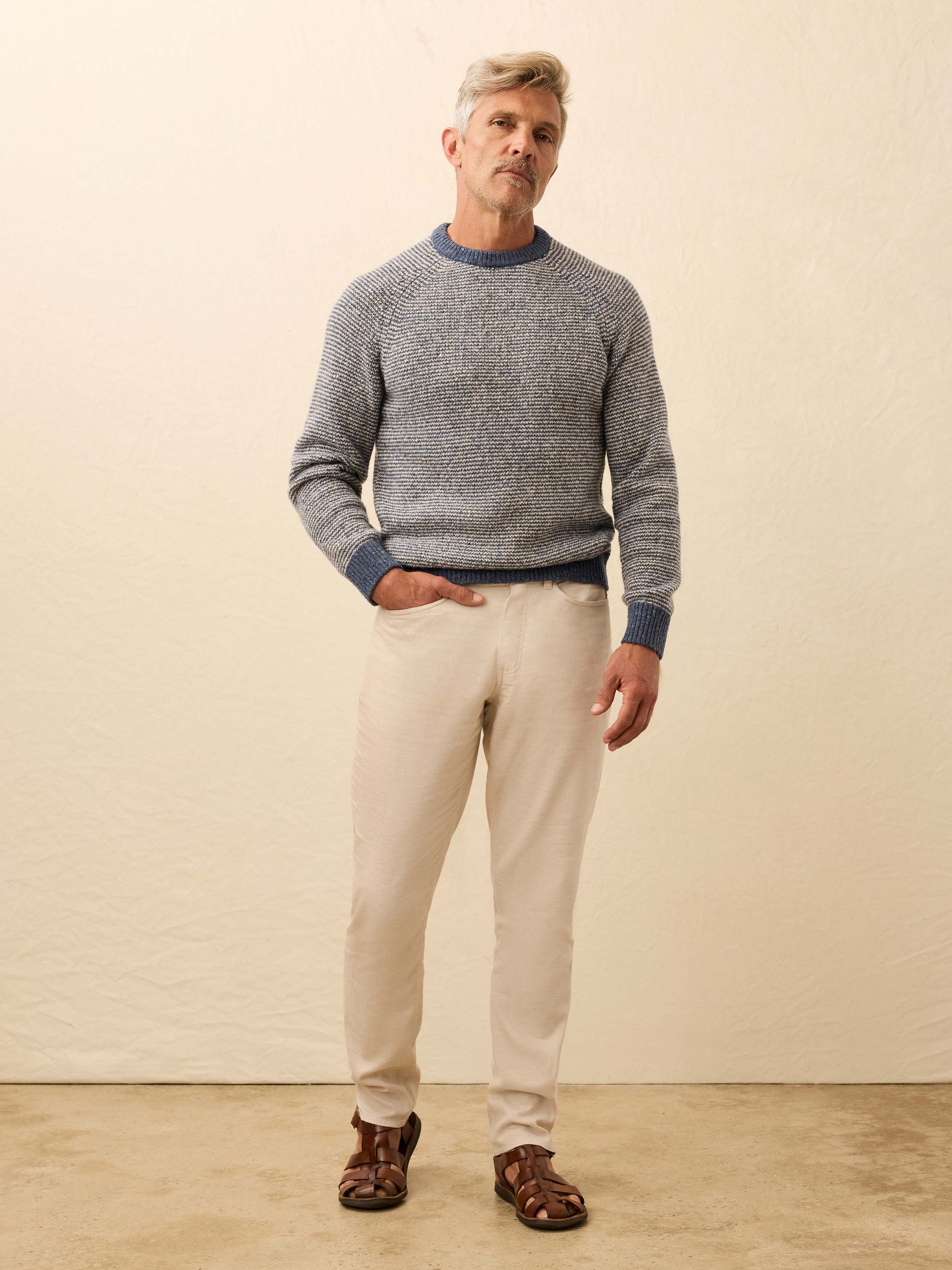 Man is wearing a blue and white sweater against a beige background