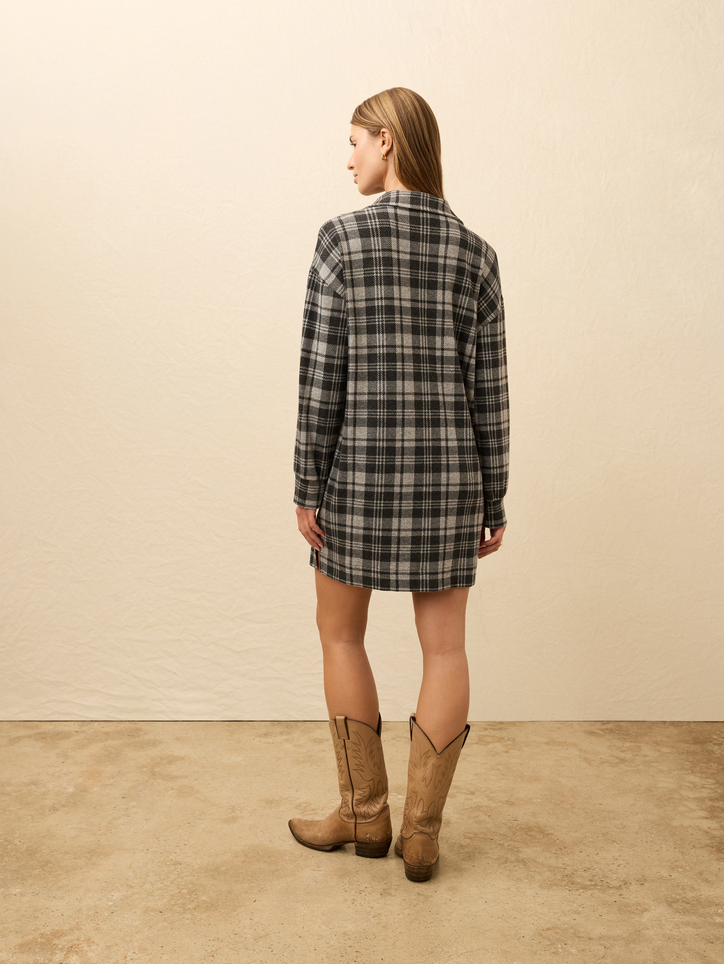 Woman wearing a plaid dress against a beige background