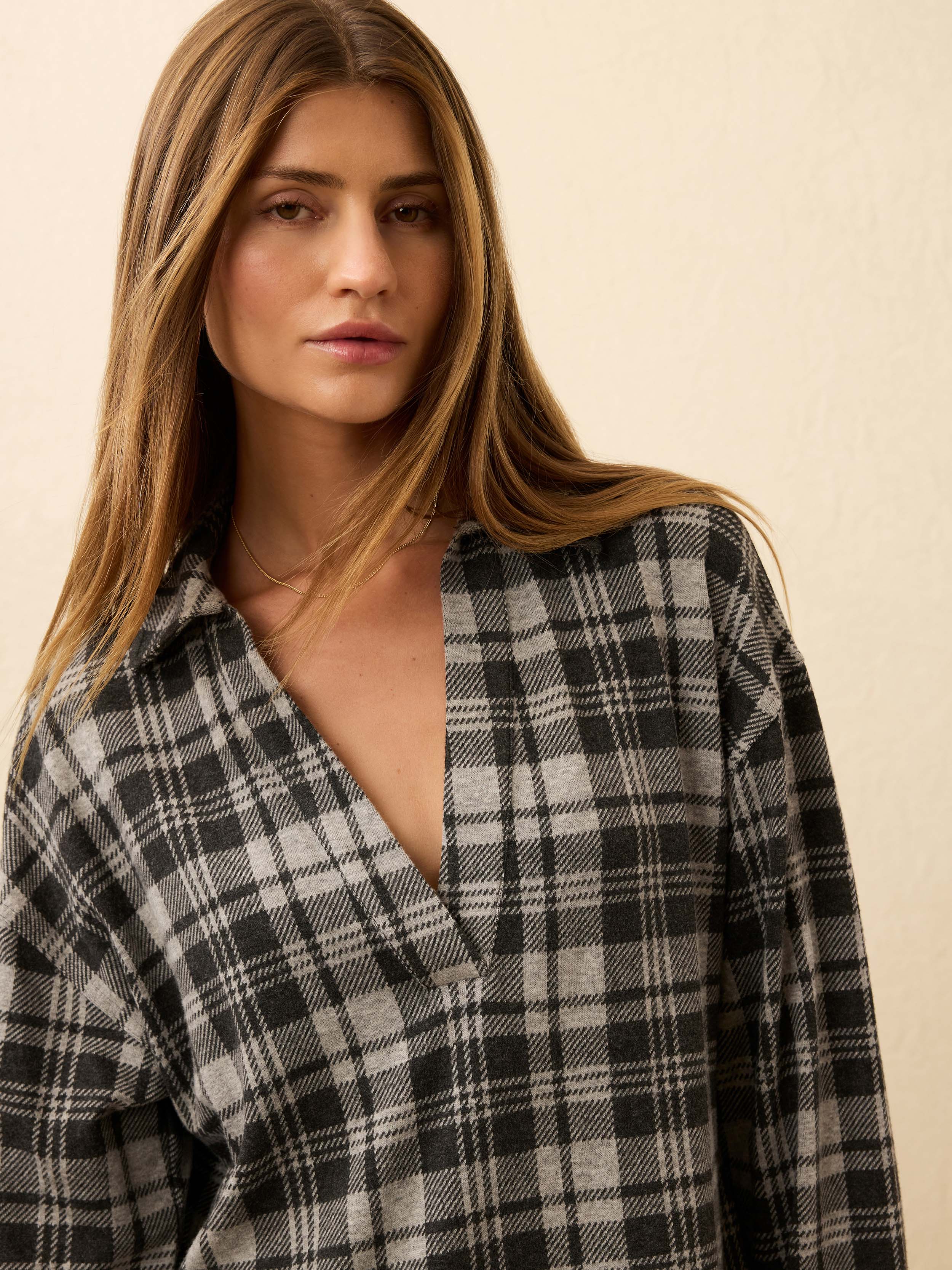 Woman wearing a plaid dress against a beige background