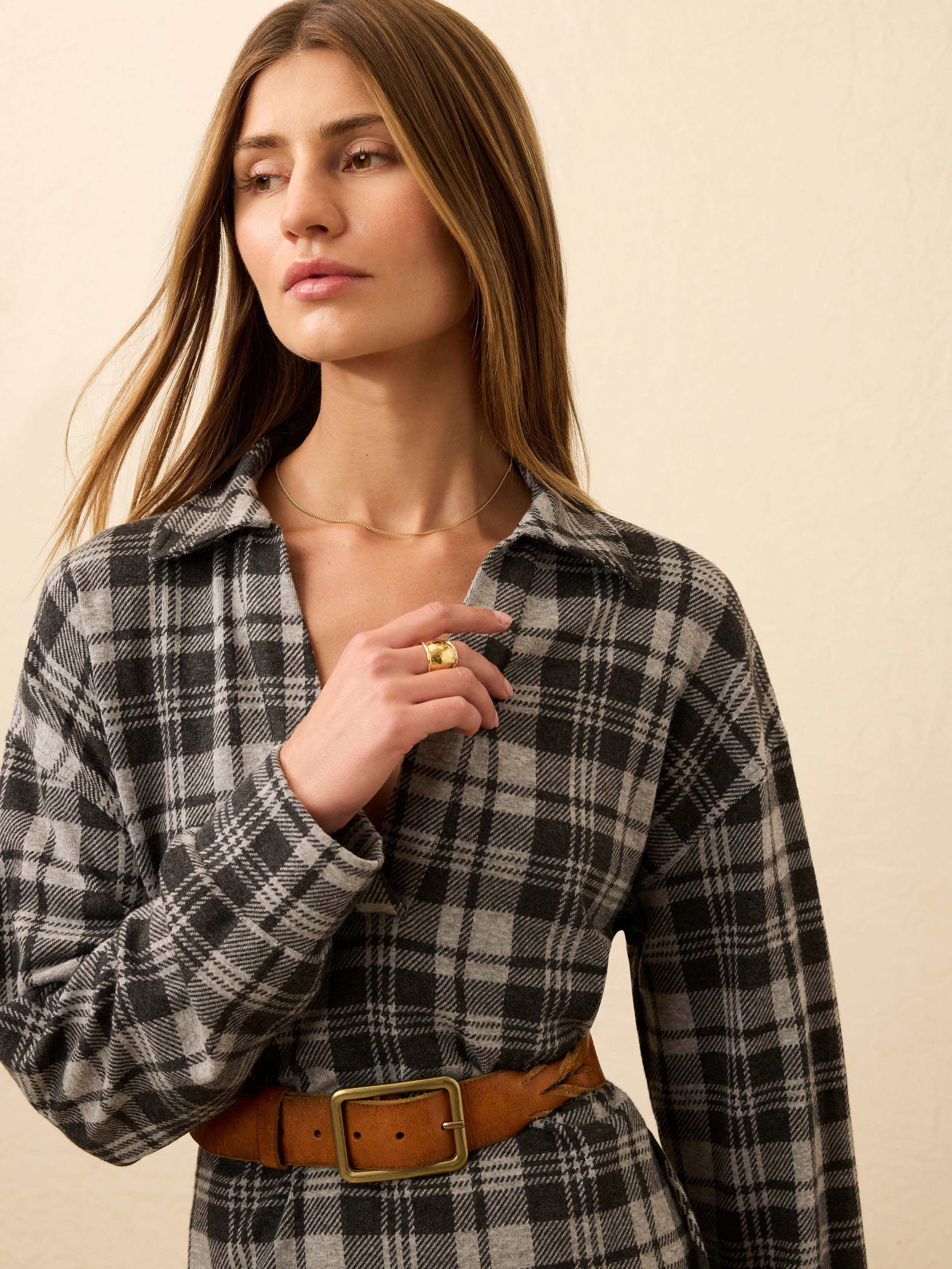 Woman wearing a plaid dress against a beige background