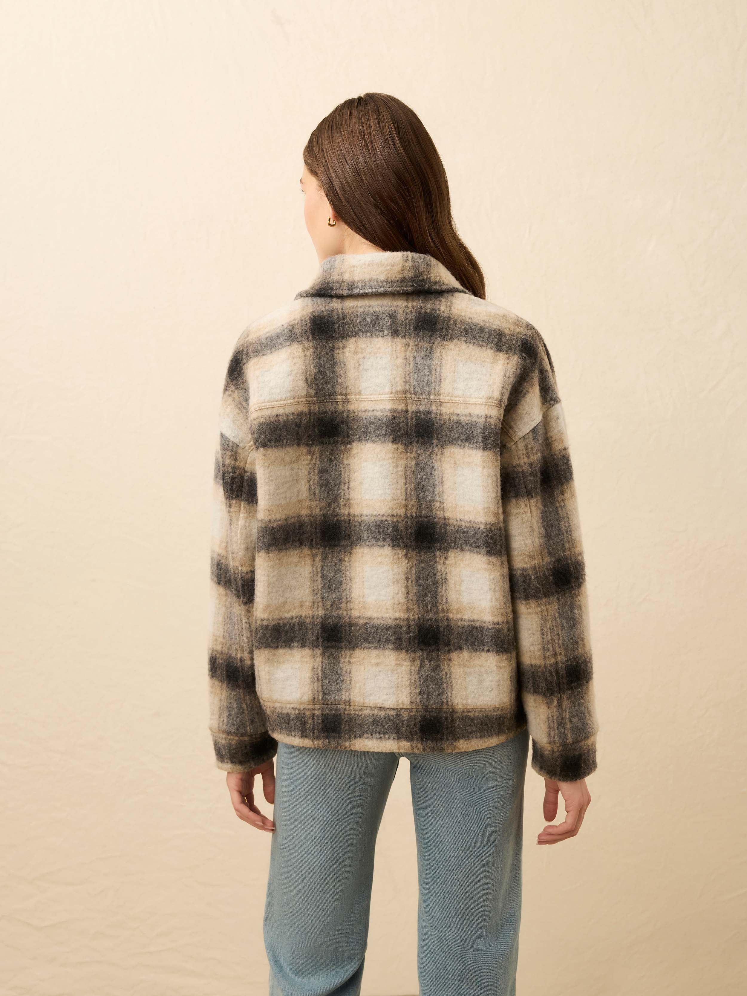 Person wearing a plaid jacket with a neutral background