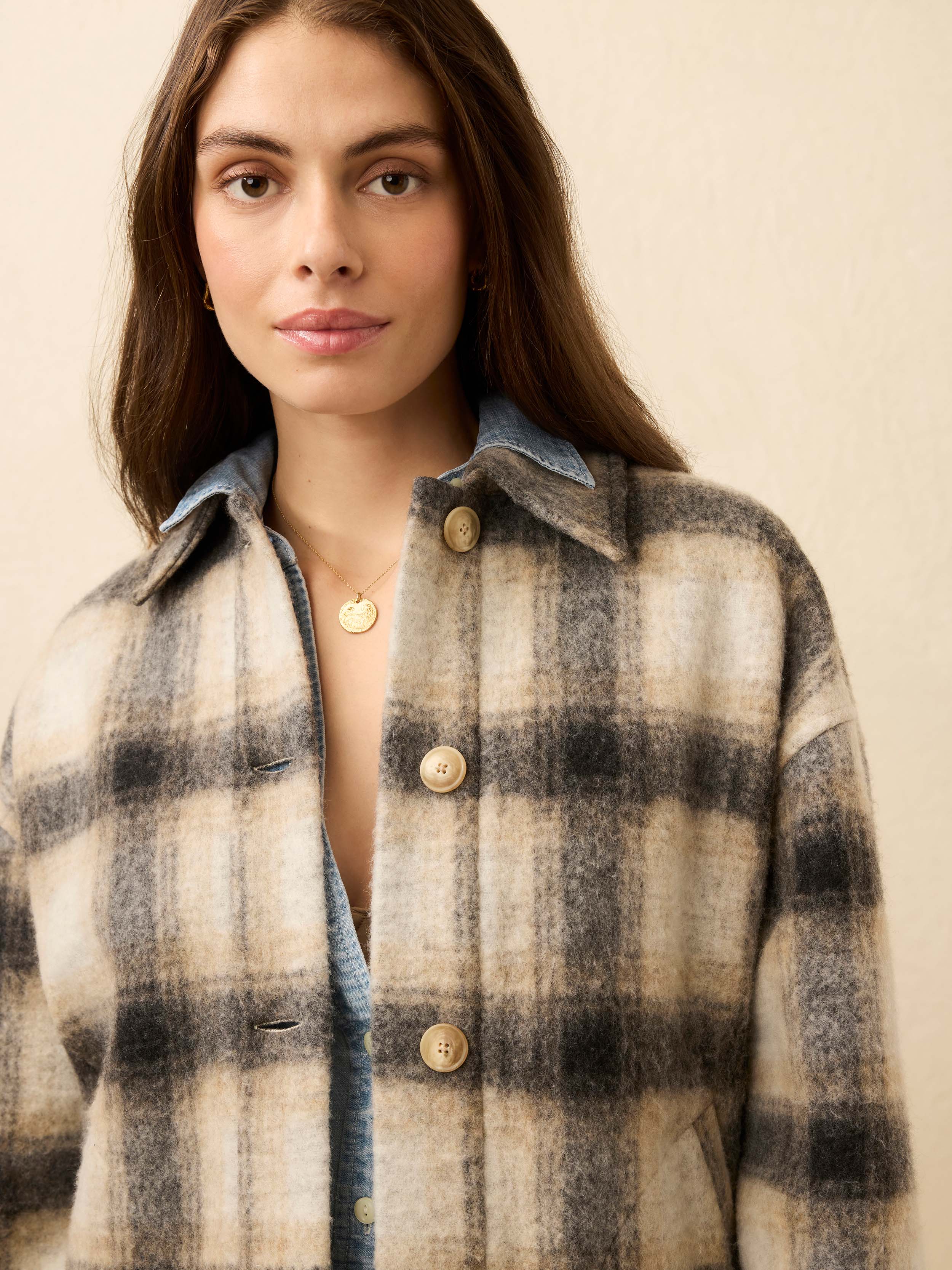 Woman wearing a plaid jacket with a neutral background