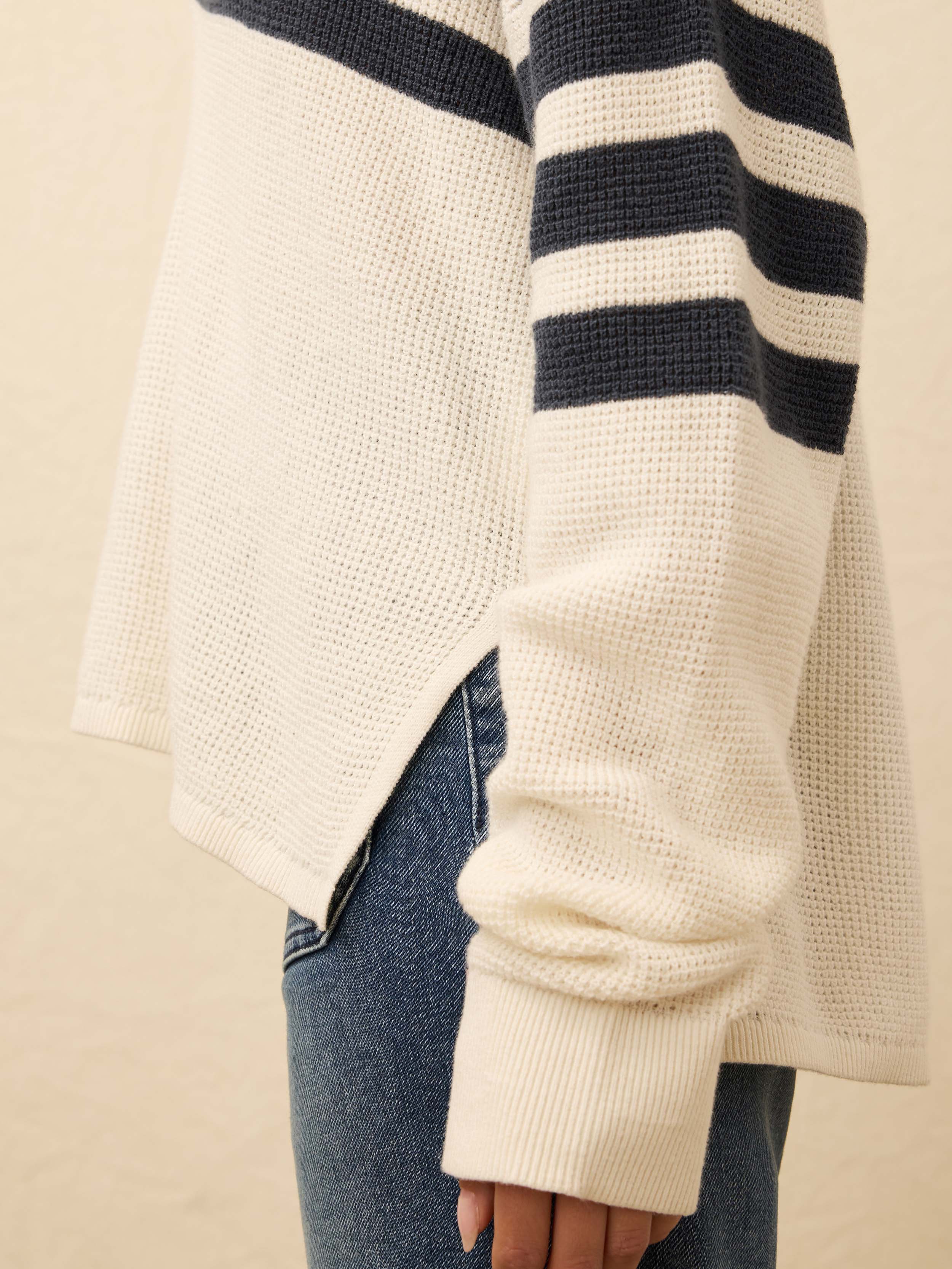 Woman wearing a navy and white striped knit against a beige background
