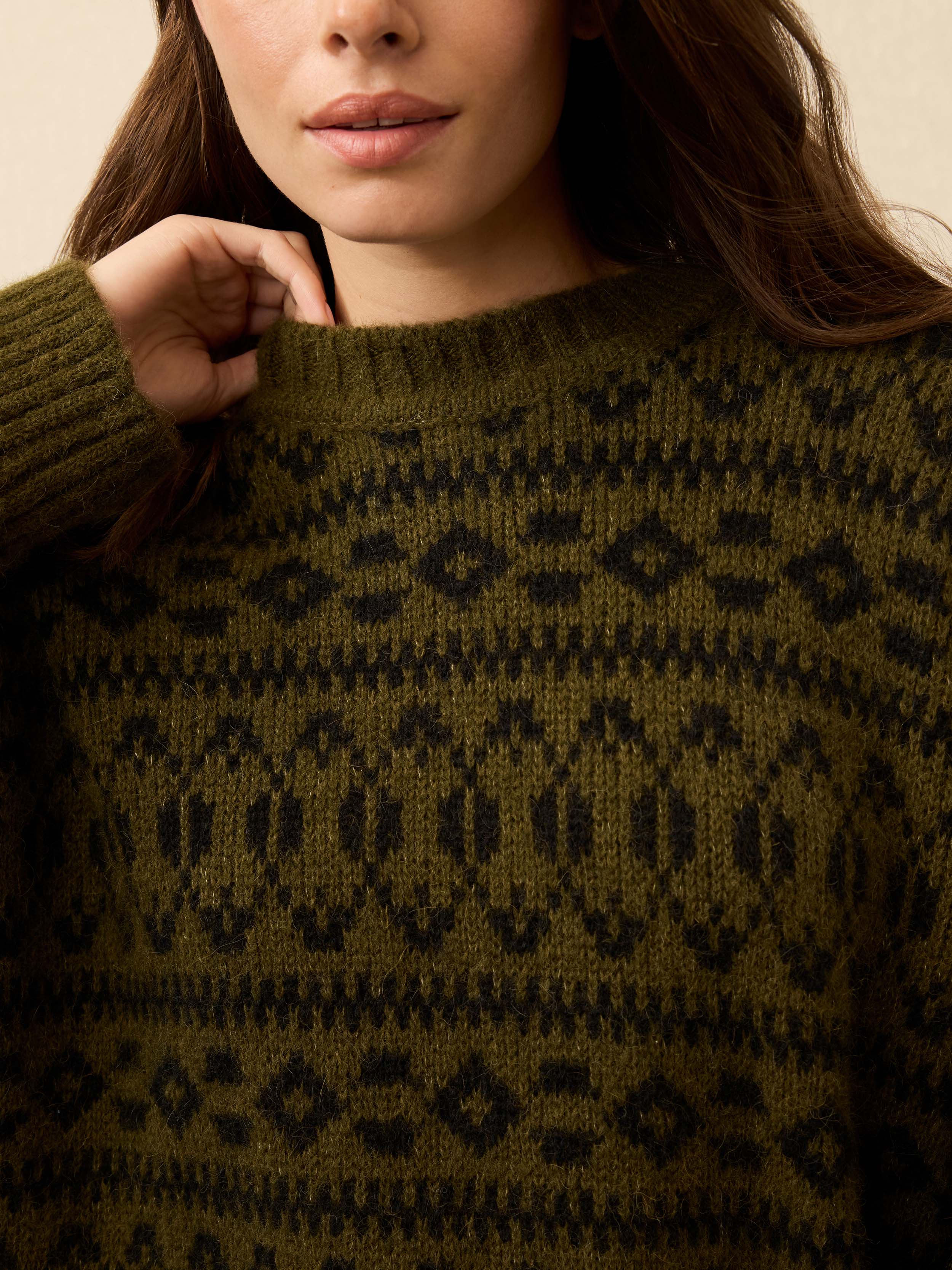 Close-up of a woman wearing a green knitted sweater with a pattern.