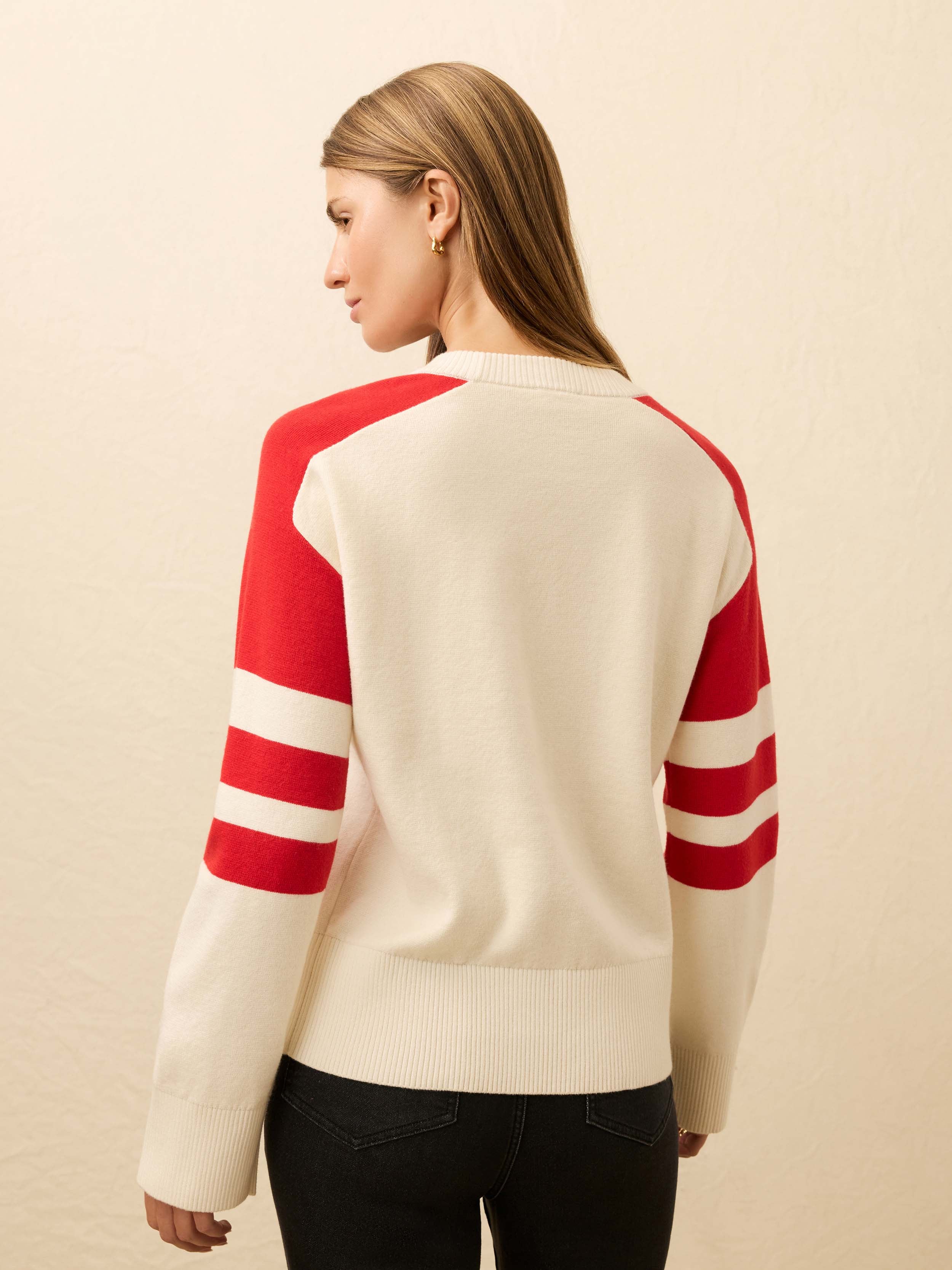 Woman wearing a cream sweater with red and white striped sleeves on a beige background