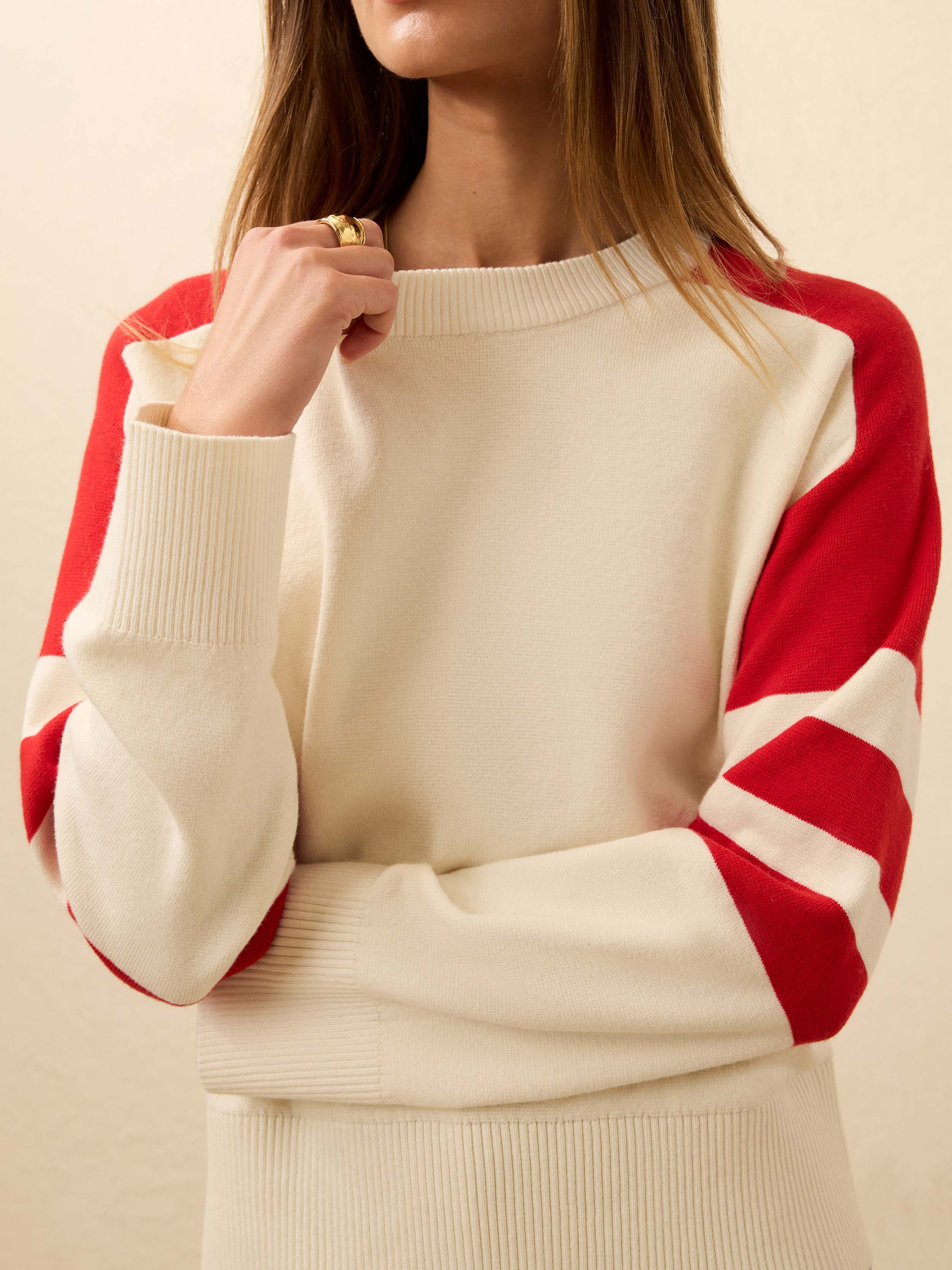 Woman wearing cream and red striped sweater against a beige background