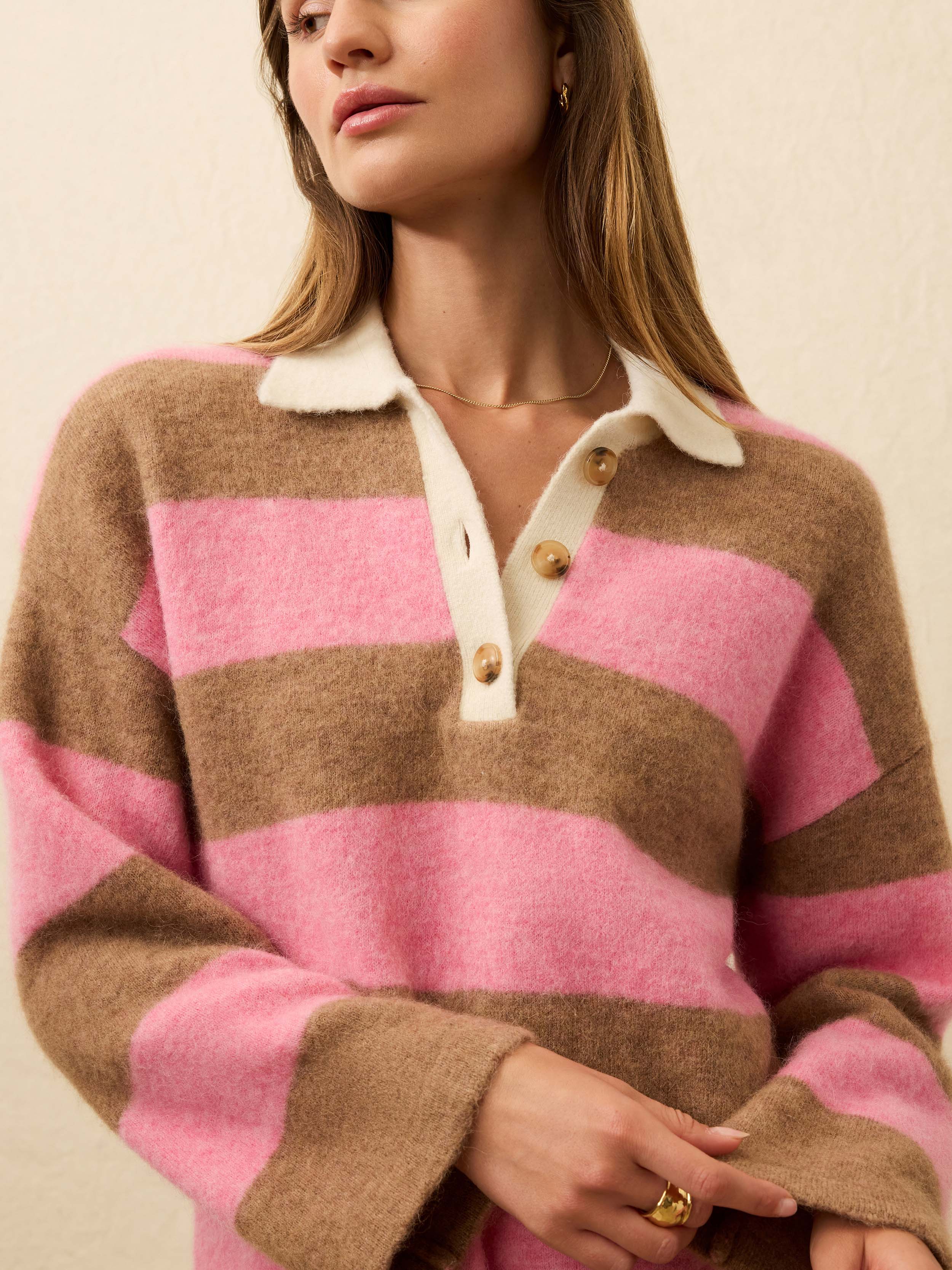 Person wearing a pink and brown striped sweater with a white collar.
