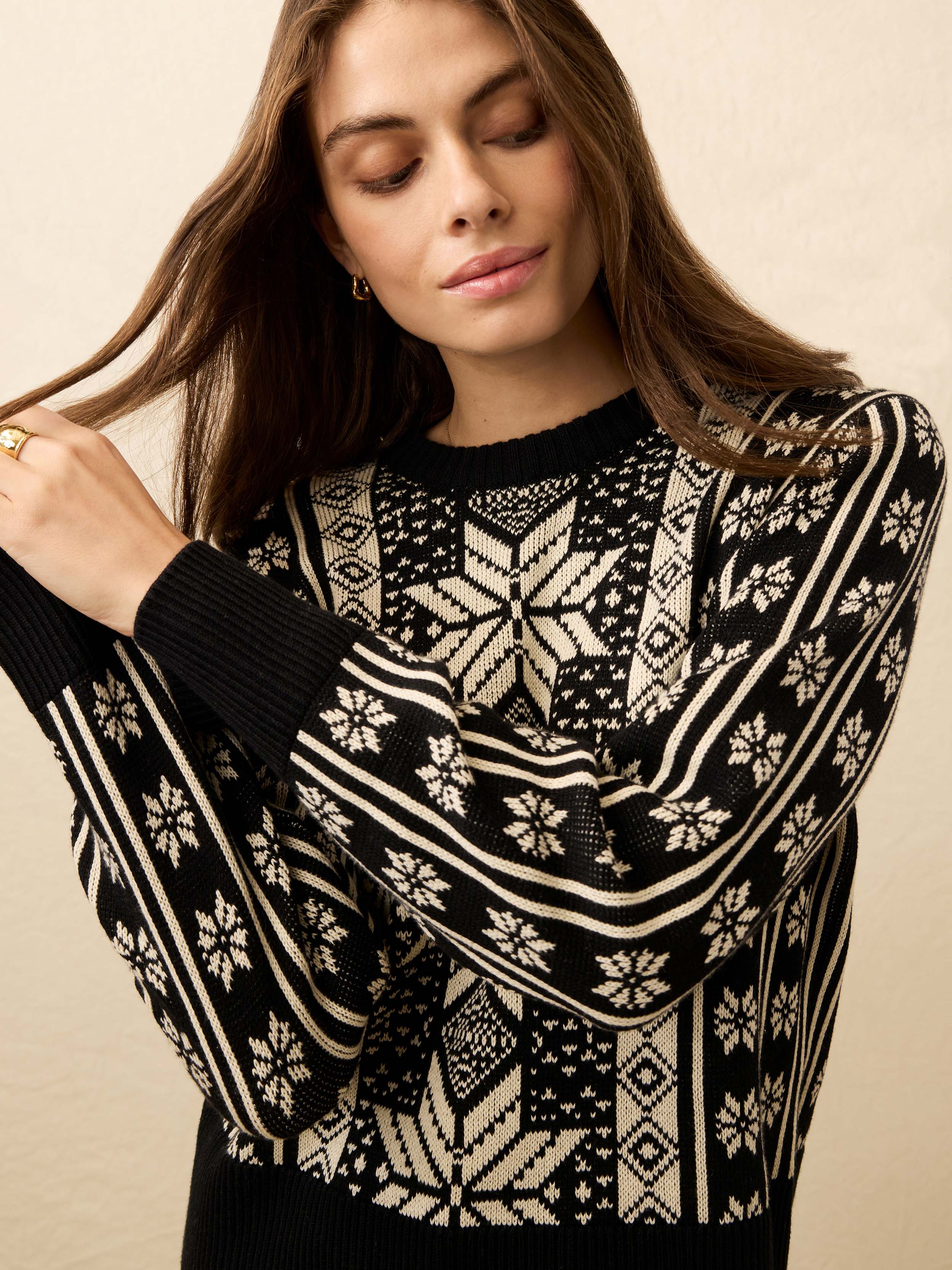 Woman wearing a black and white patterned sweater against a beige background
