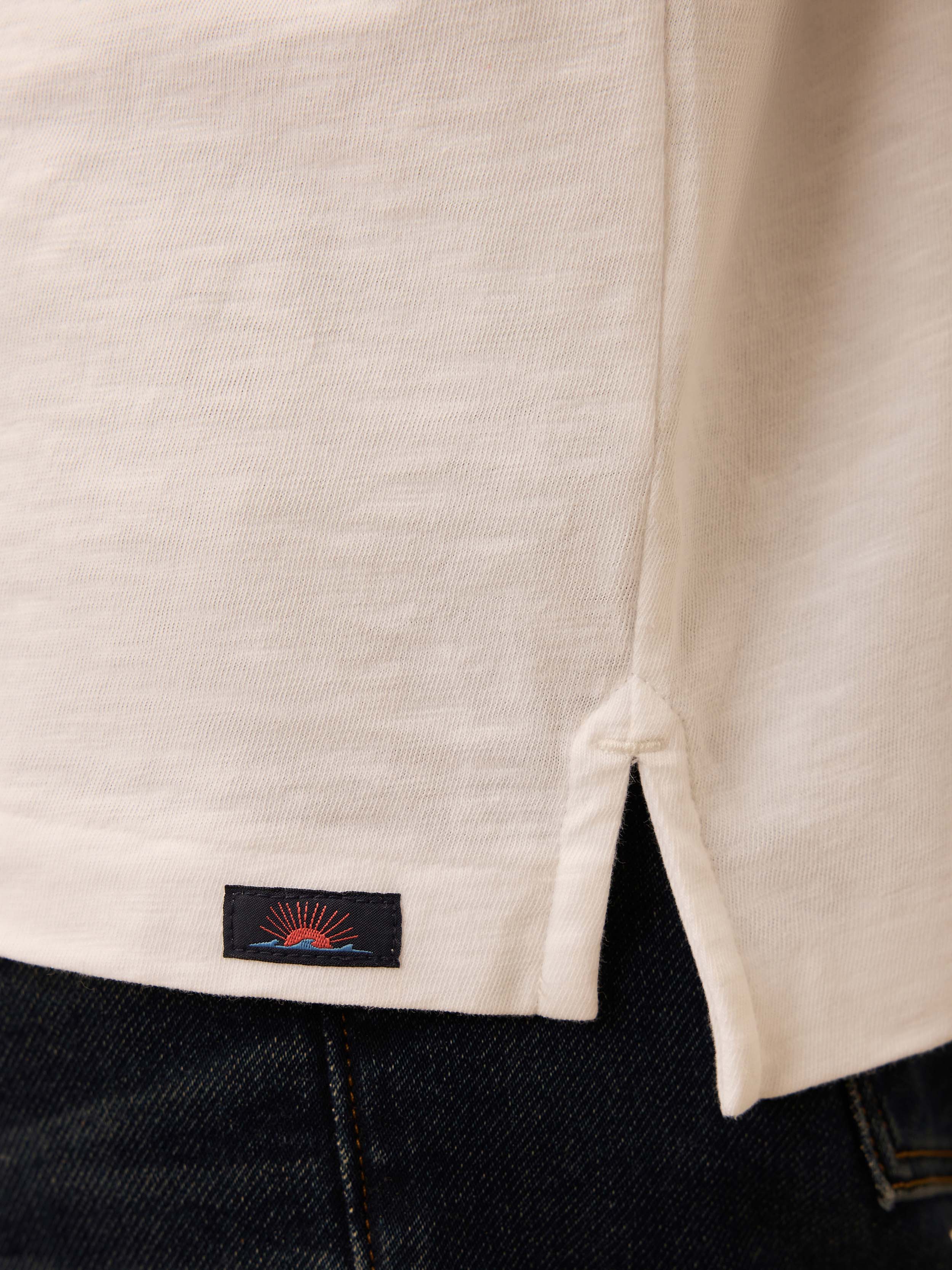 Close-up of a white polo shirt with a Faherty brand logo