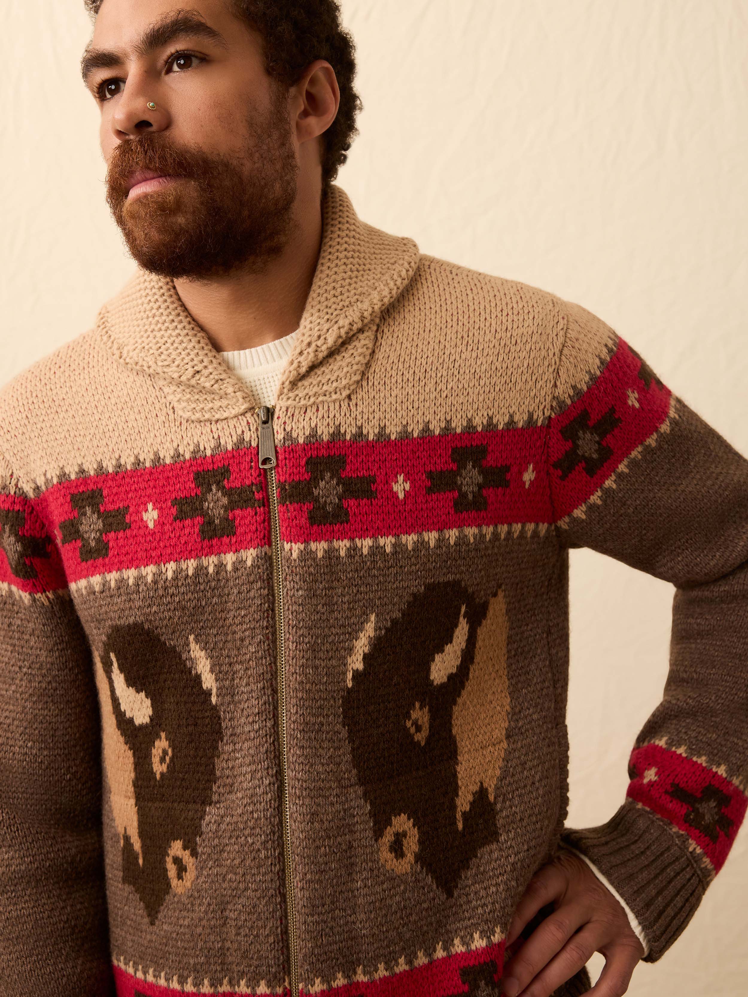 Man wearing a buffalo patterned cardigan against a beige background
