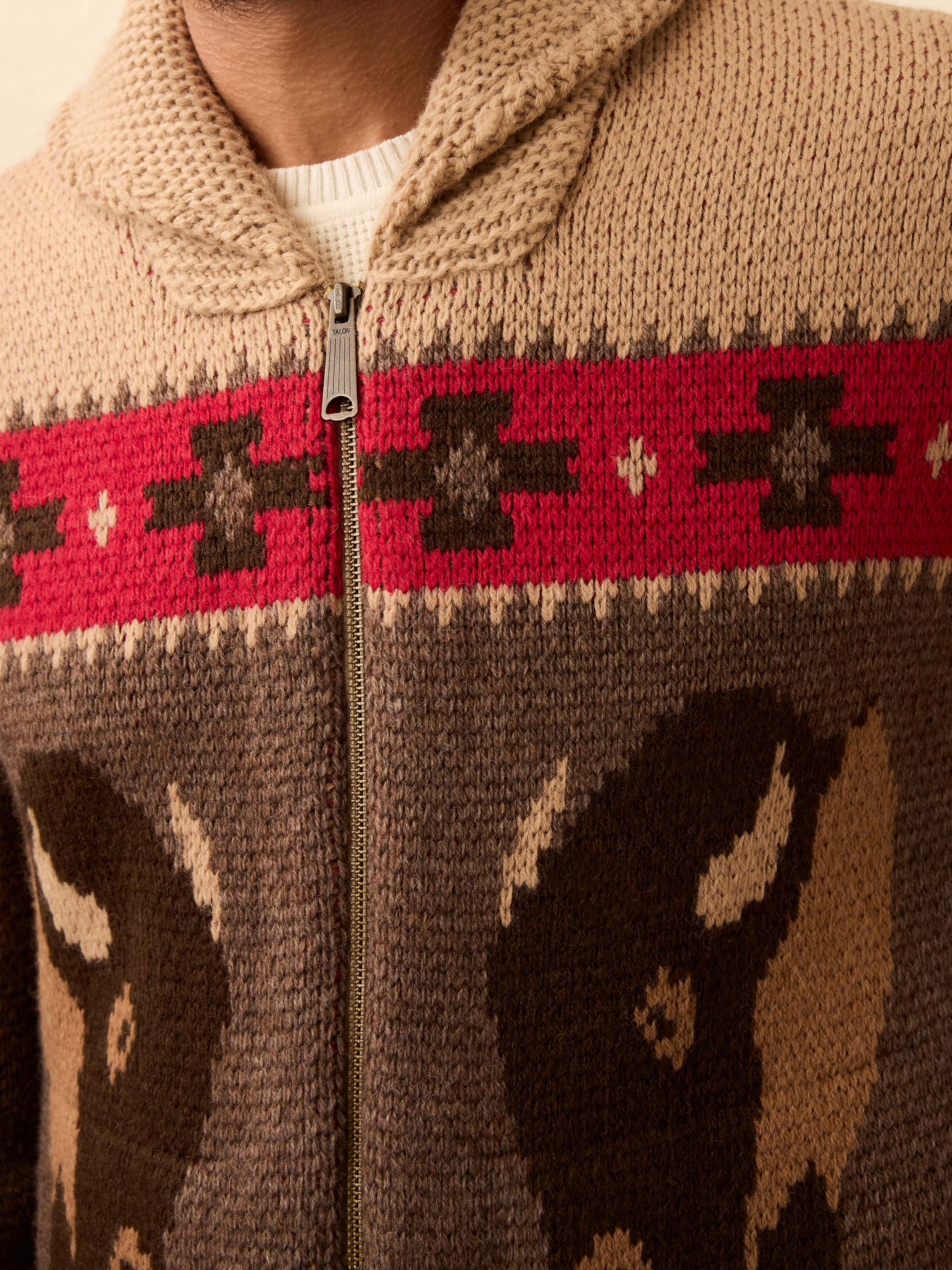 Close-up of a person wearing a brown knit sweater with a buffalo patterned design.