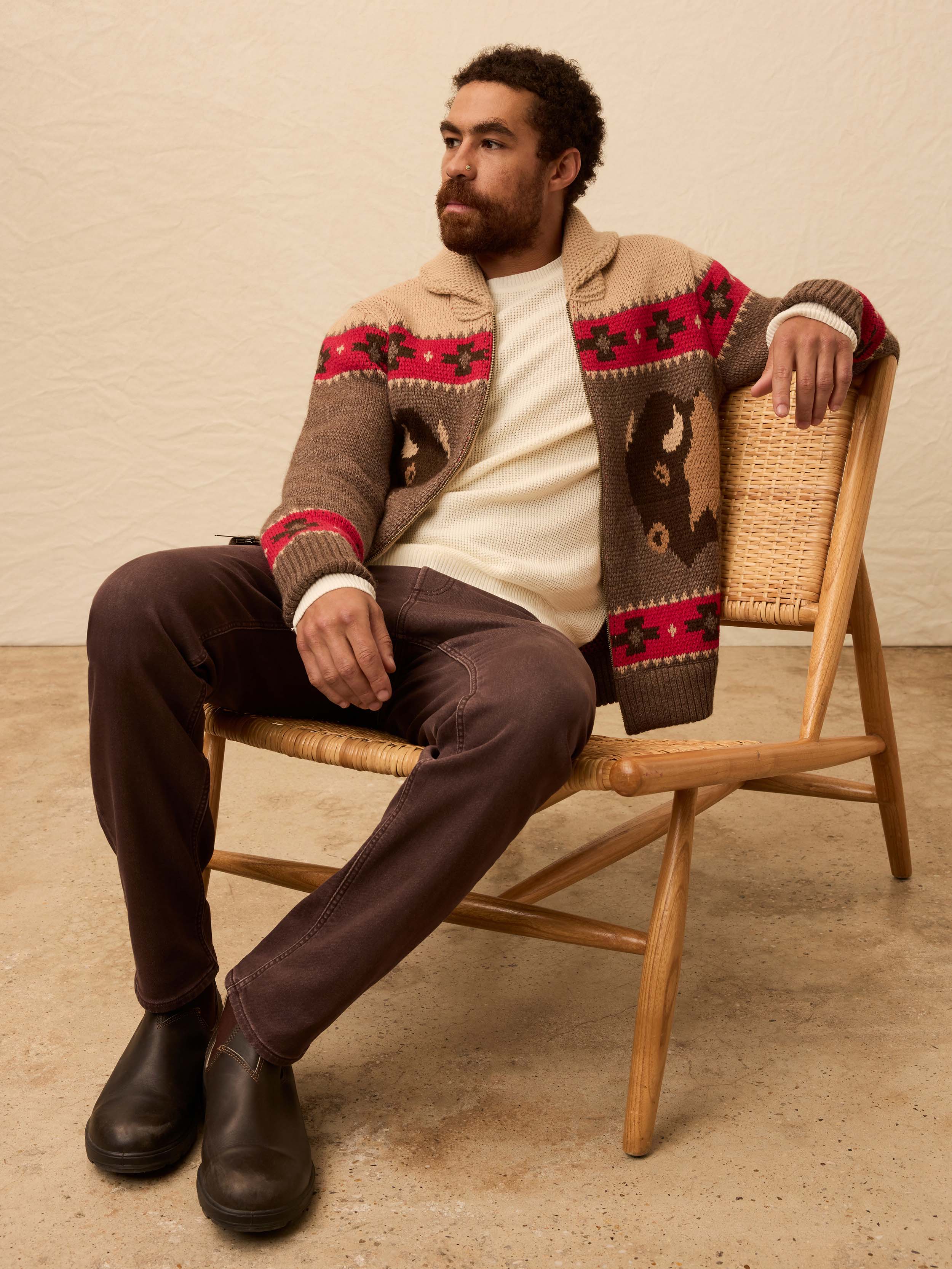 Man wearing a buffalo patterned cardigan against a beige background