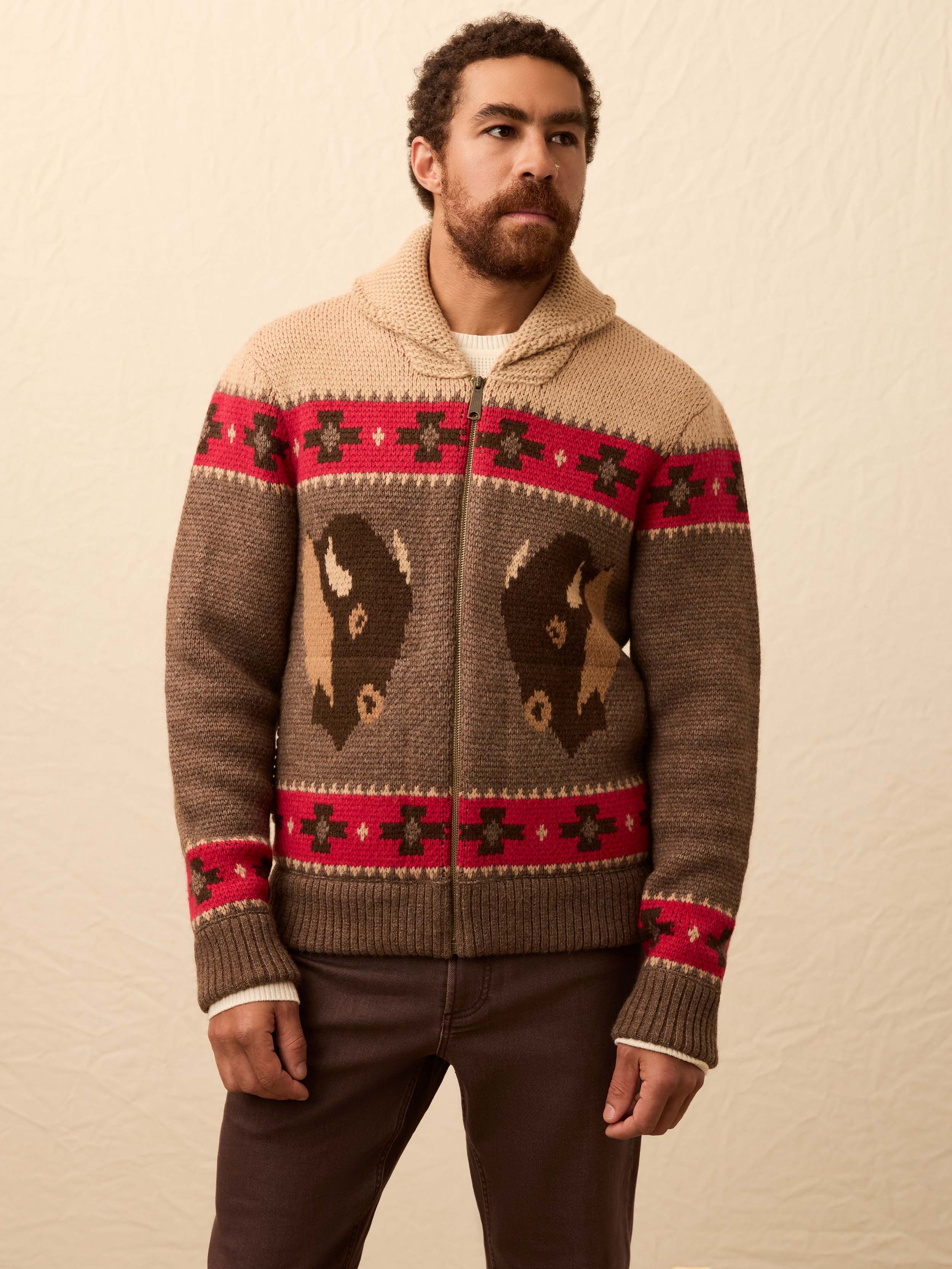 Man wearing a buffalo patterned cardigan against a beige background